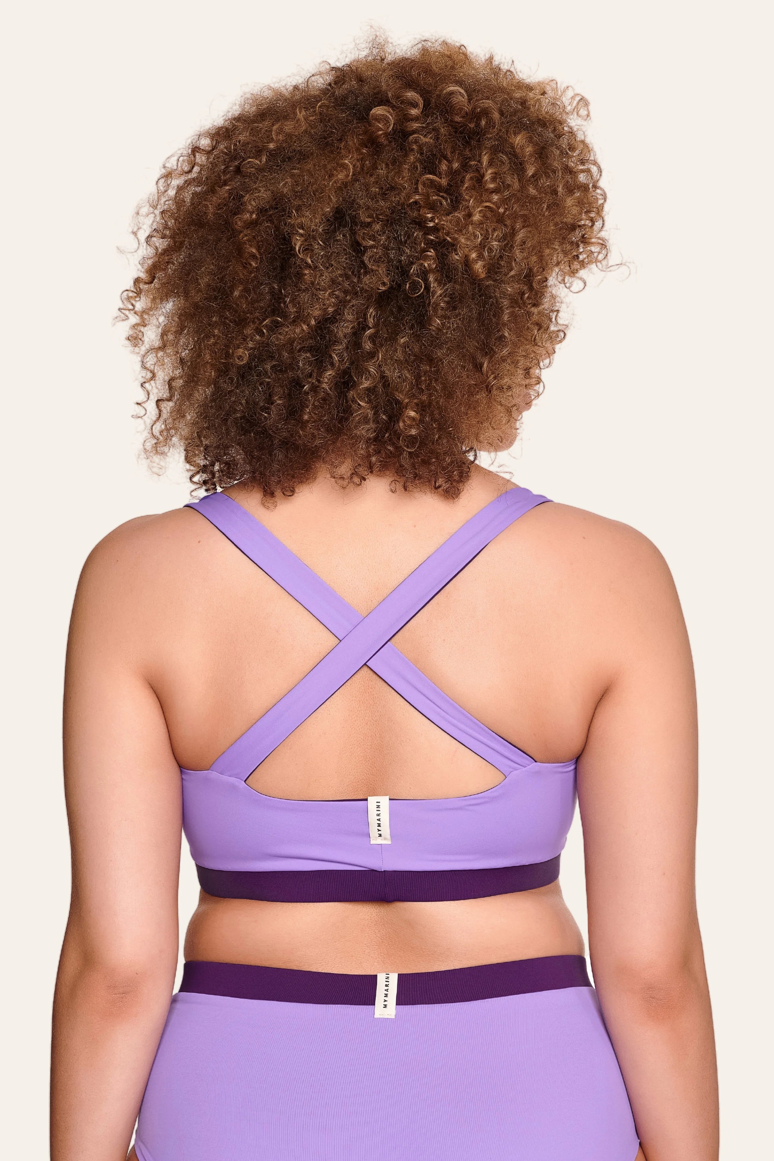 Person von hinten in lila MYMARINI Bikinitop mit breiten, überkreuzten Trägern und passender Bikinihose.#color_lavender-plum