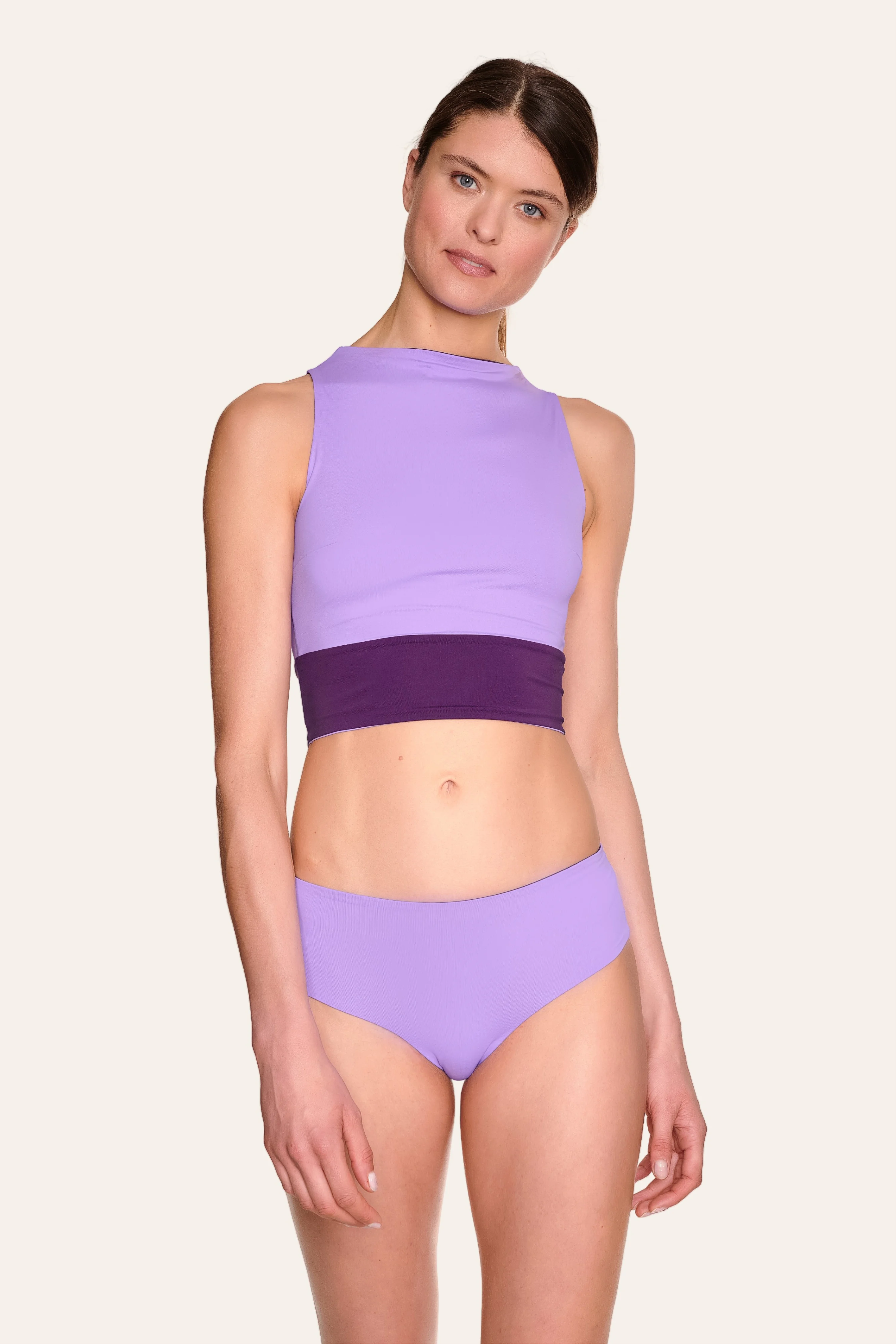 Frau trägt MYMARINI Bikini mit hochgeschlossenem Top und Mid-Rise-Hose in Lila.#color_lavender-plum