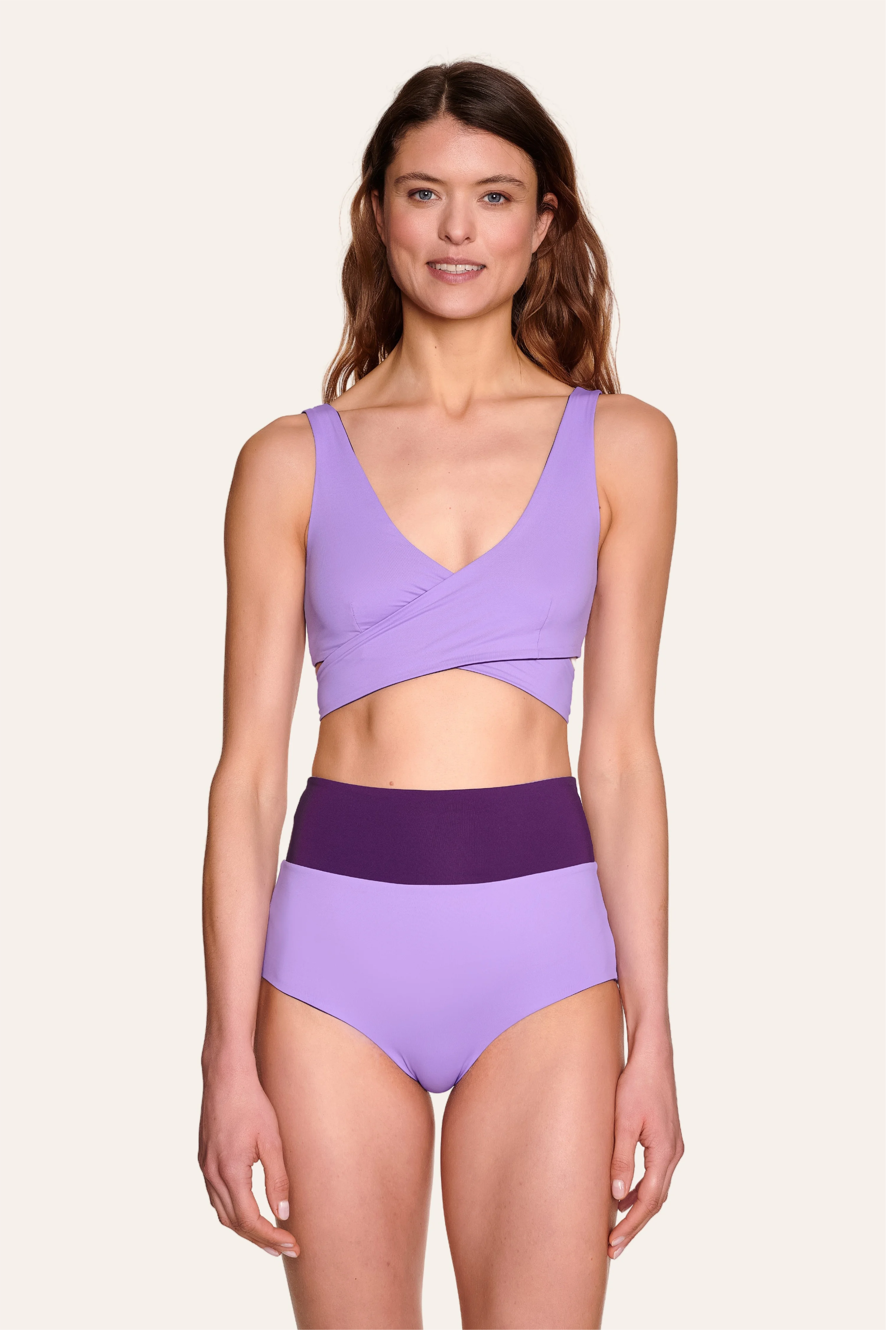 Frau trägt MYMARINI Bikini mit V-Ausschnitt und High Waist Schnitt in Lila.#color_lavender-plum