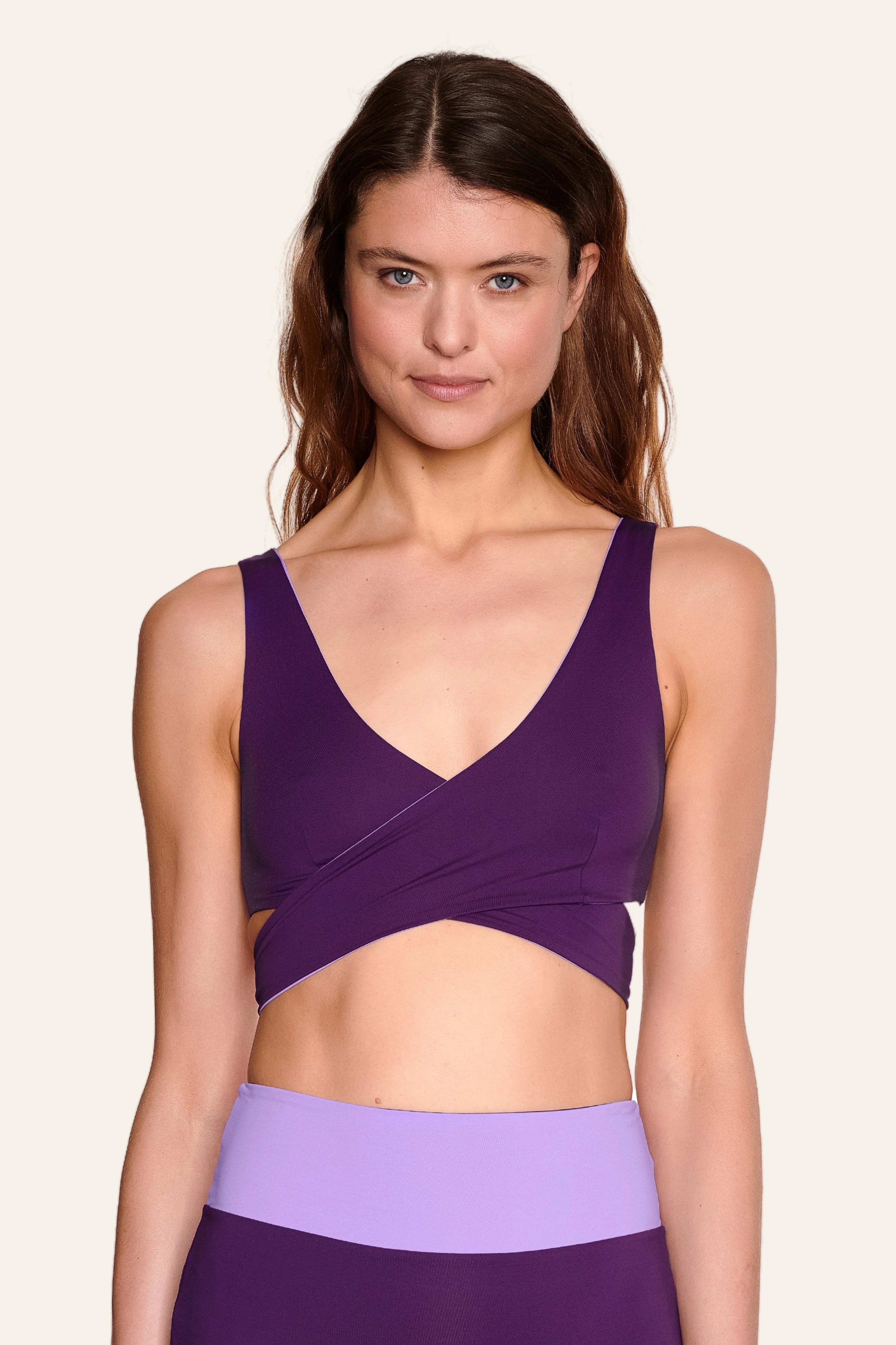 Frau trägt lila MYMARINI Bikinitop mit V-Ausschnitt und breiten Trägern.#color_lavender-plum