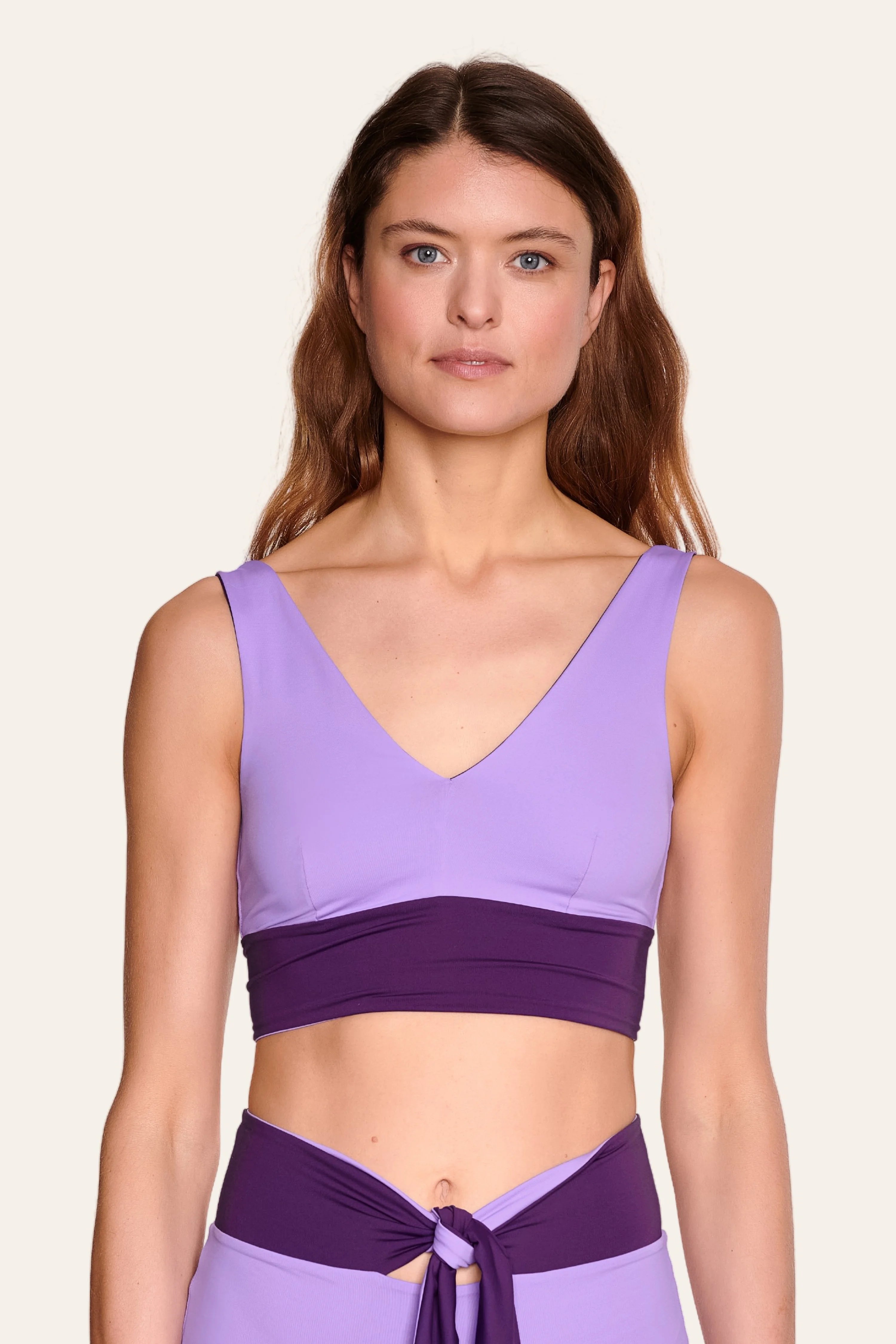 Frau trägt MYMARINI Bikinitop mit V-Ausschnitt und breiten Trägern in Lila.#color_lavender-plum