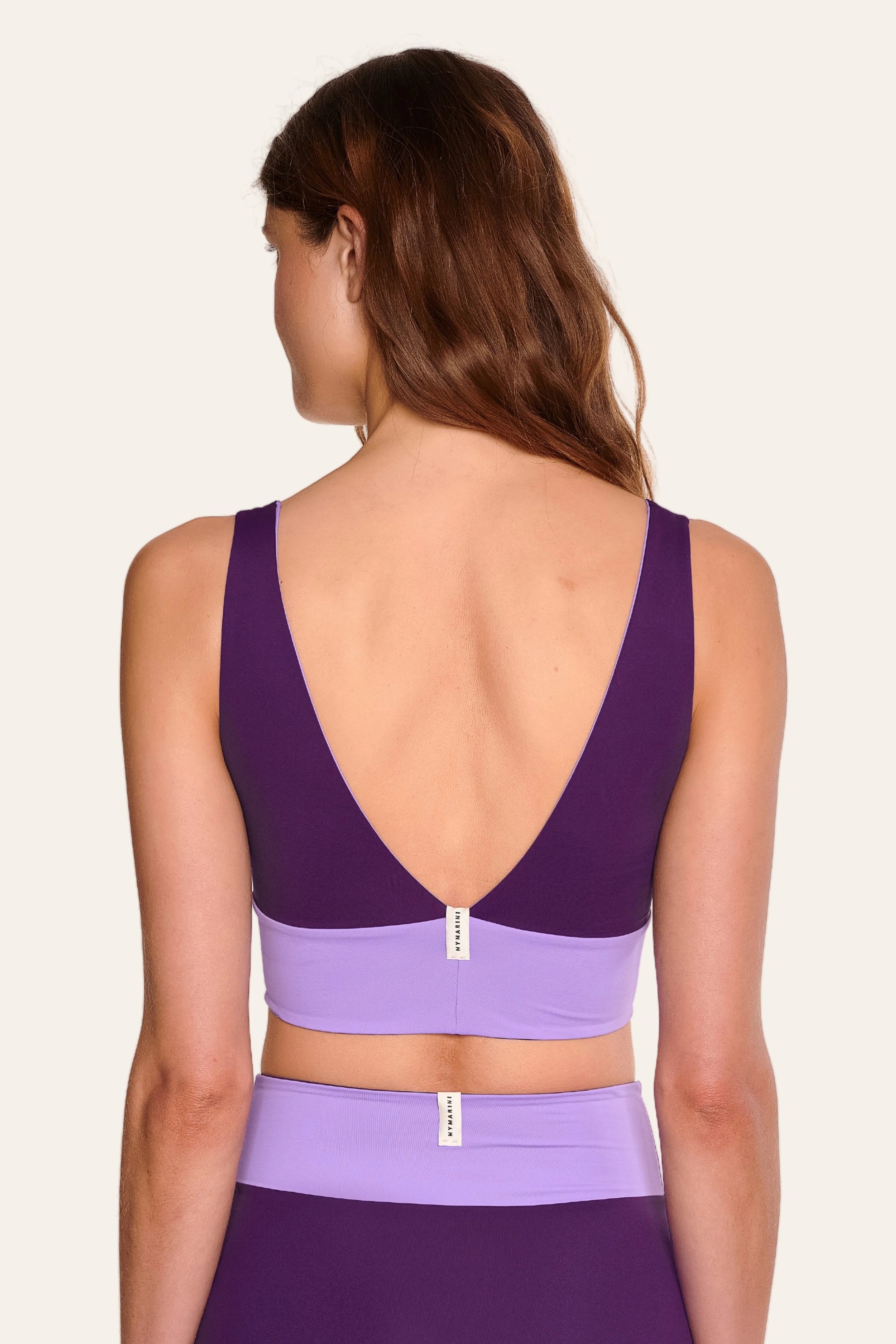 Frau trägt MYMARINI Bikinitop mit tiefem Rückenausschnitt und breiten Trägern in Lila.#color_lavender-plum