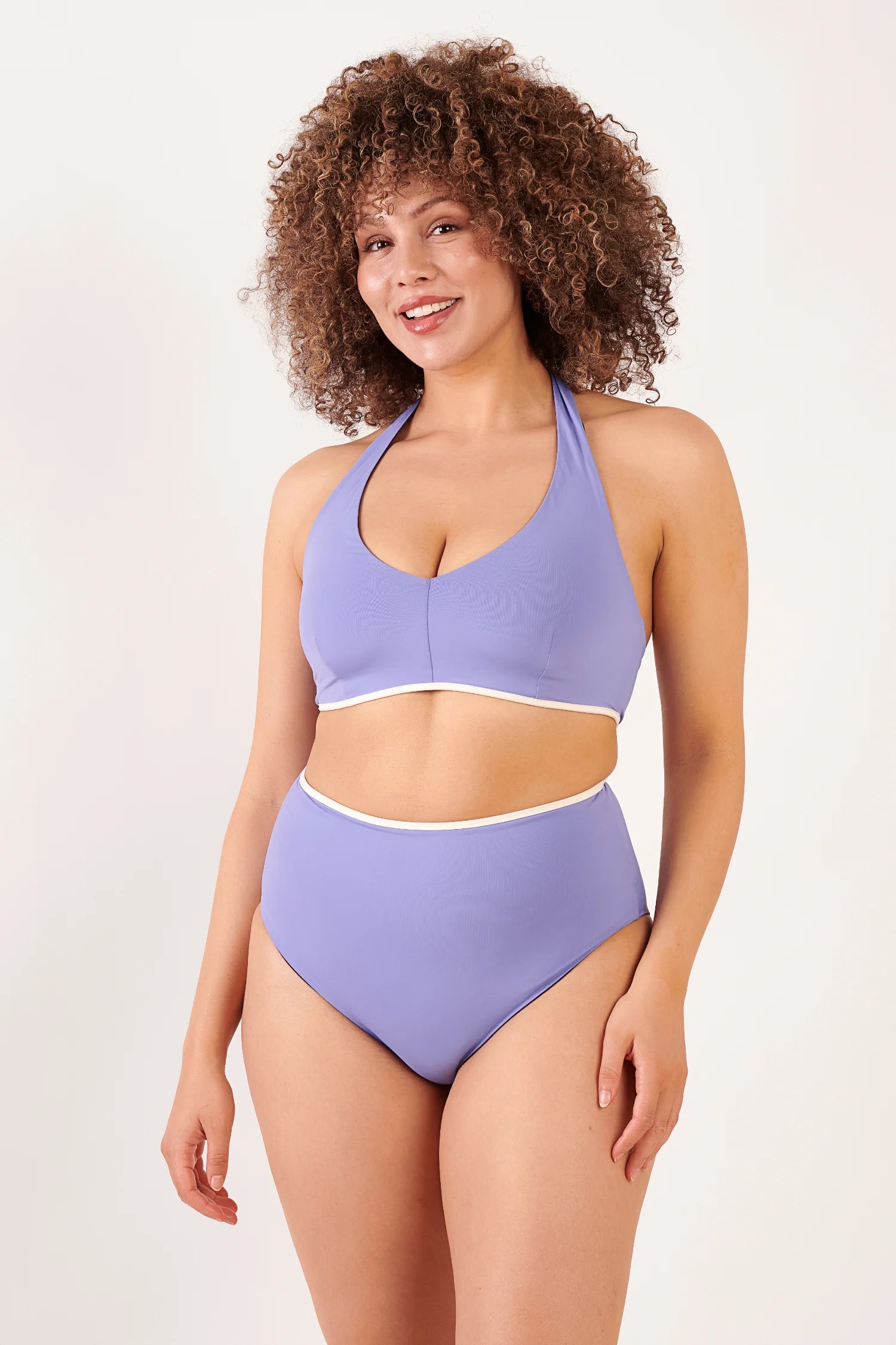 MYMARINI Bikinioberteil in Flieder mit Halterneck und V-Ausschnitt; High-Waist-Bikinihose mit weißer Naht, getragen von einer Frau mit lockigem Haar.#color_chocolate-lilac