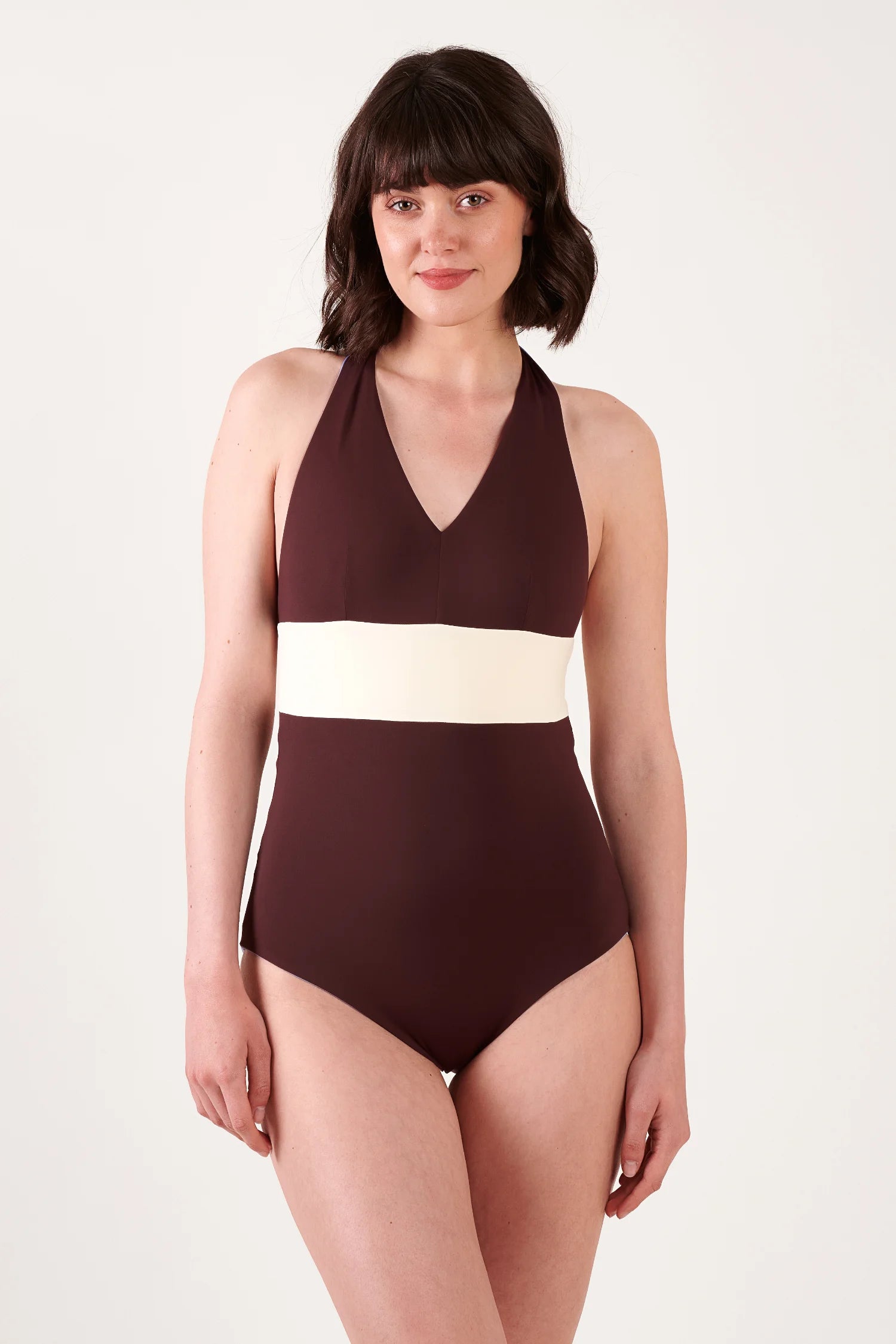 MYMARINI One-Piece Badeanzug in Dunkelbraun mit cremefarbener Taille, V-Ausschnitt, breite Träger, an einer Frau getragen.#color_chocolate-lilac
