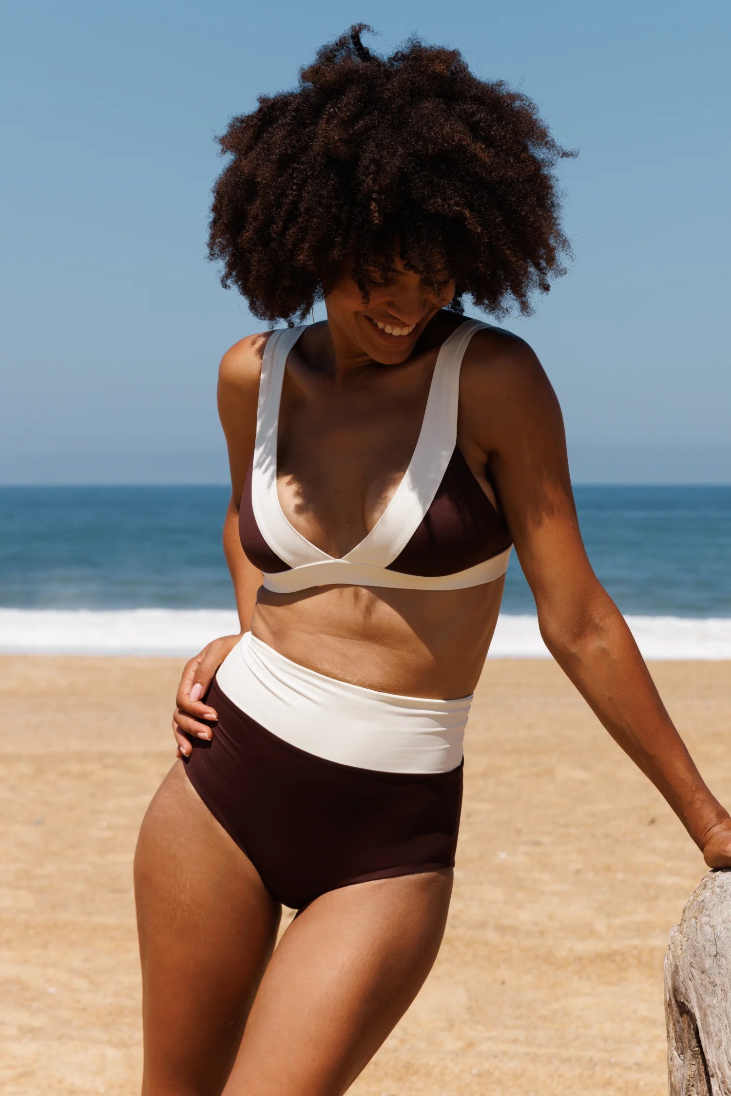 MYMARINI Bikini-Top mit V-Ausschnitt und breiten Trägern; Bikinihose mit hohem Bund, zweifarbig braun-creme am Strand.#color_chocolate-lilac