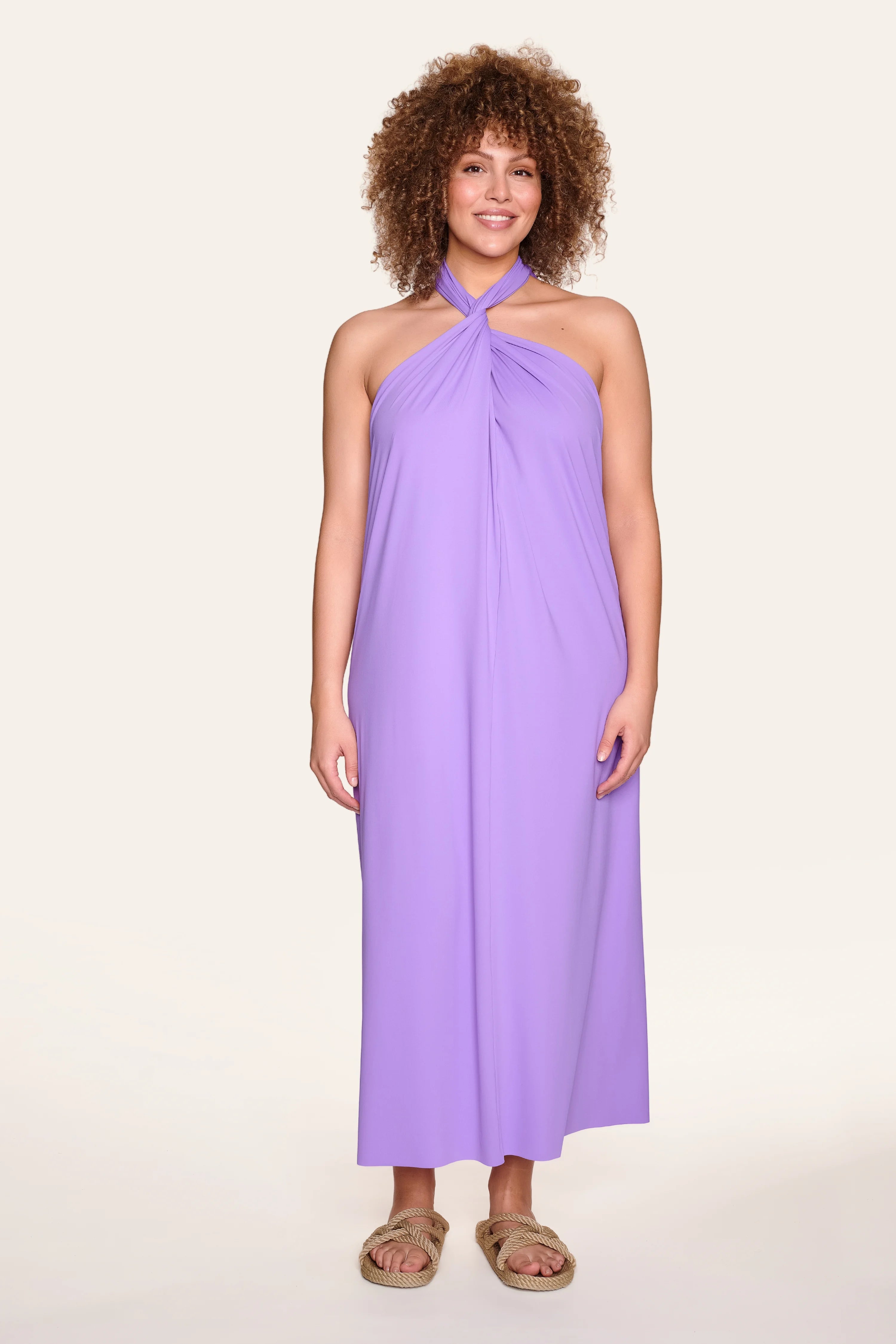 Person trägt ein lila MYMARINI Neckholder-Kleid, stehend vor hellem Hintergrund.#color_lavender