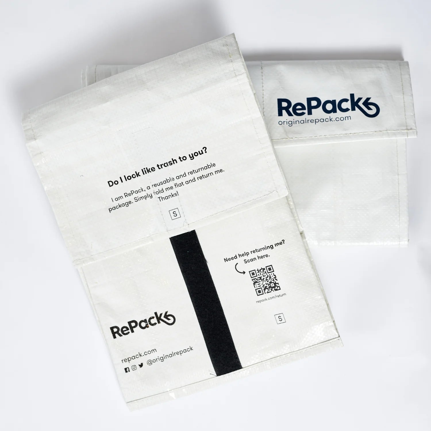 Nachhaltige Verpackung von RePack in Weiß mit schwarzem Aufdruck, flach hingelegt.