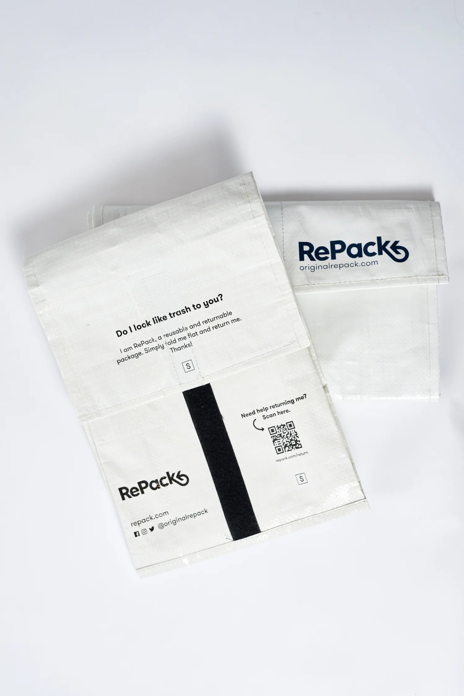 Nachhaltige Verpackung von RePack in Weiß mit schwarzem Aufdruck, flach hingelegt.