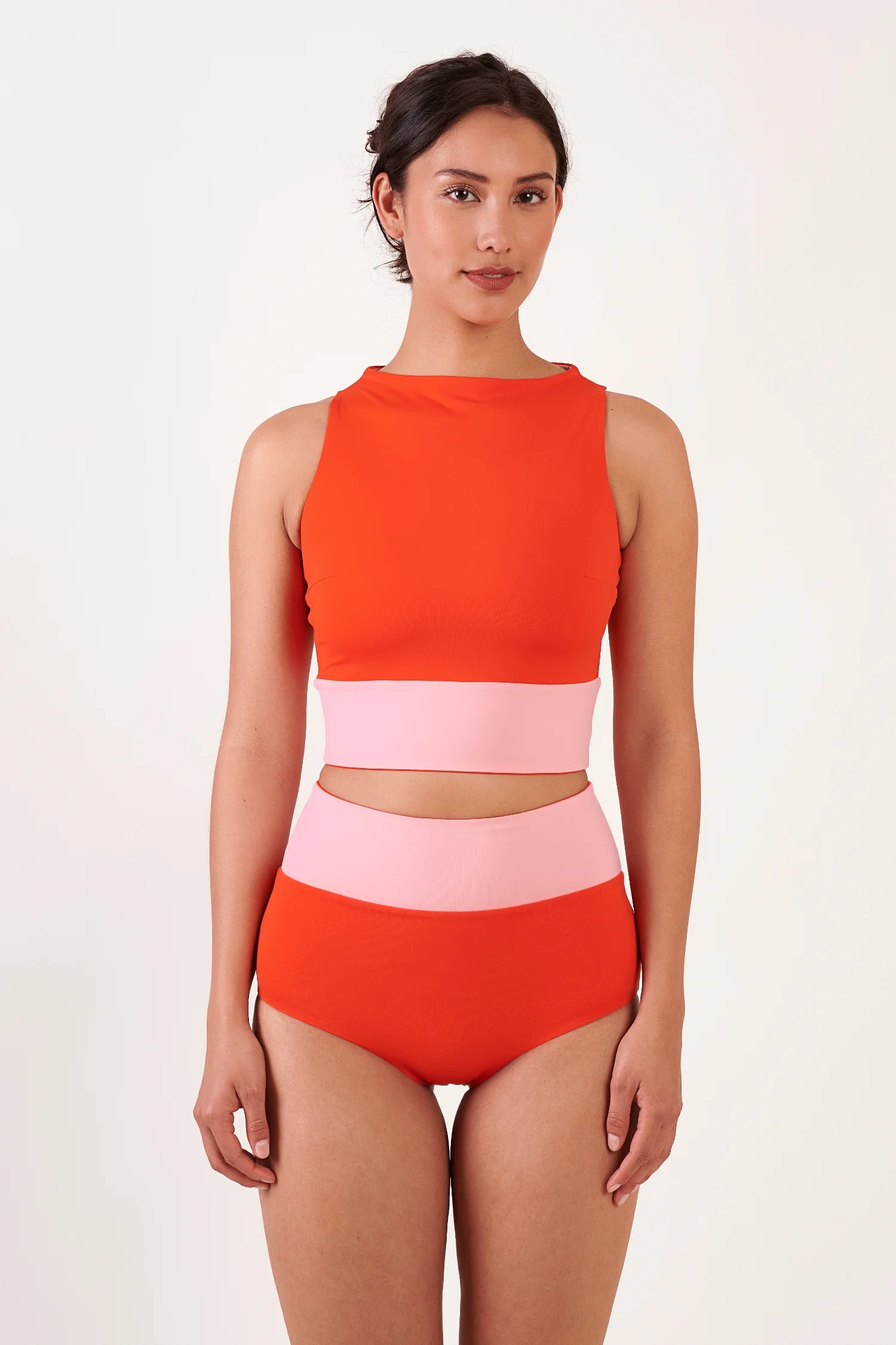 MYMARINI Bikini-Top in Orange mit hohem Hals, dazu Bikinihose in Orange mit rosa Mittelteil – Modell frontal.#color_poppy-macaron