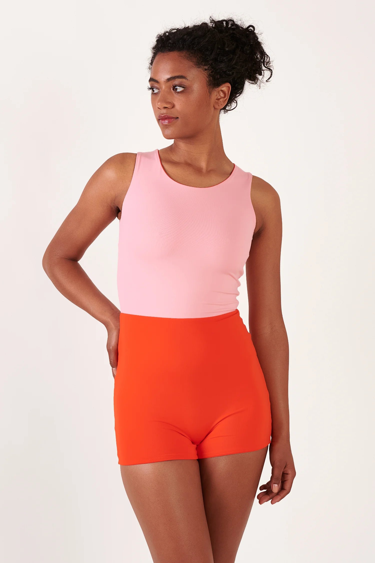 MYMARINI Top und Shorts: hellrosa ärmelloses Top mit Rundhalsausschnitt, orange High-Waist-Shorts; Modell steht seitlich.#color_poppy-macaron