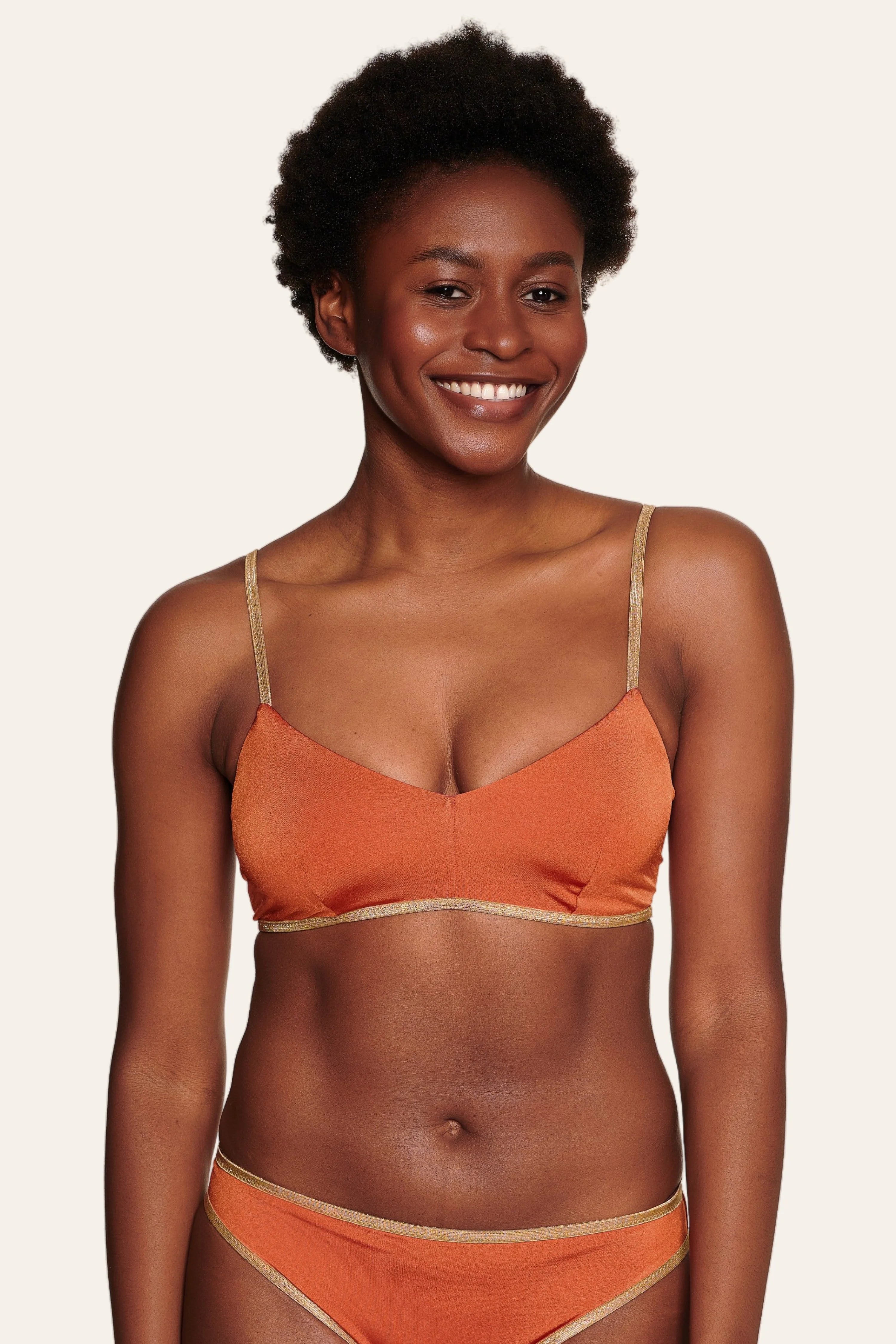 Frau trägt MYMARINI Bikinitop mit Spaghettiträgern und Bikinihose in Orange.#color_papaya-cassis