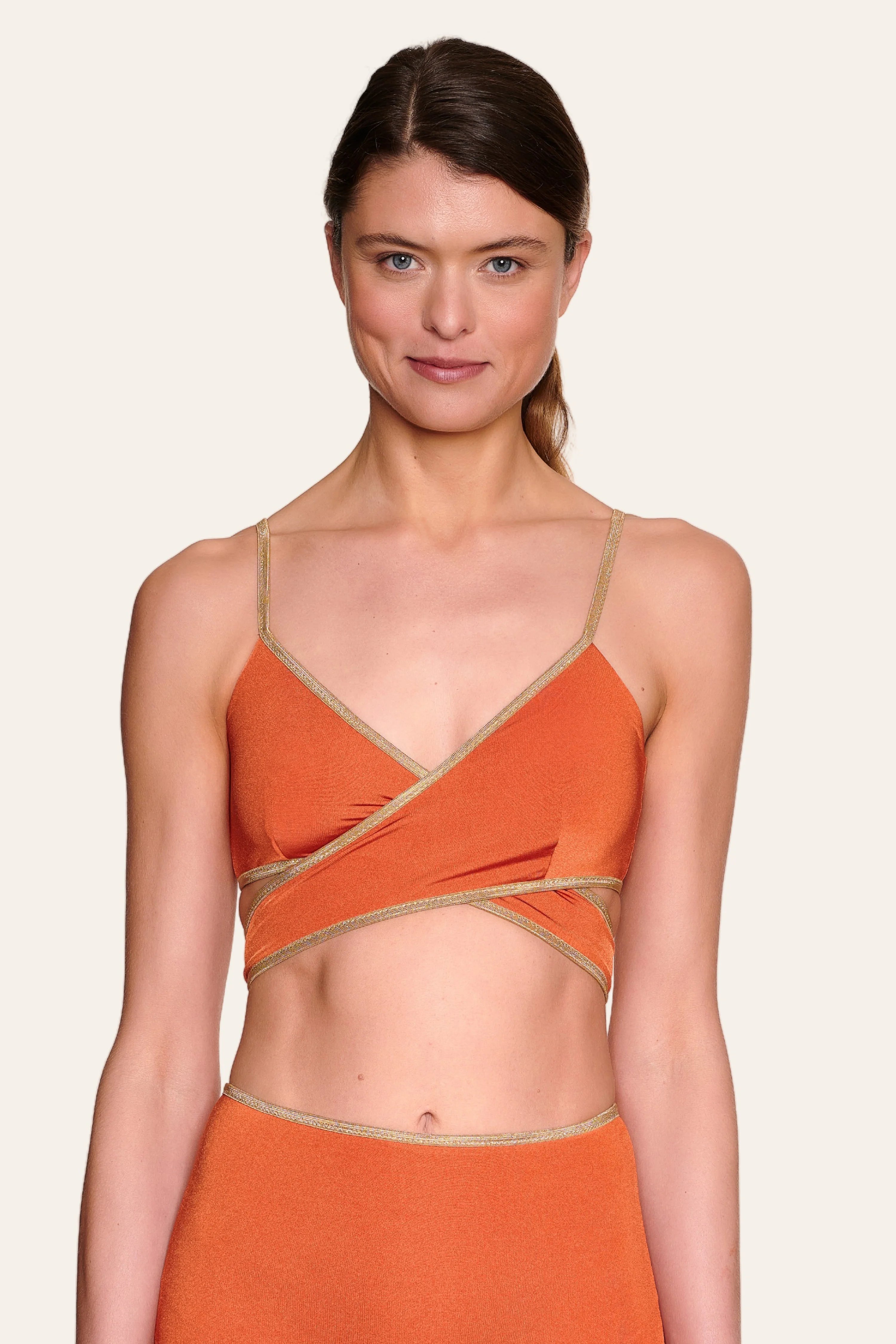 Frau trägt MYMARINI Bikinitop mit V-Ausschnitt und Spaghettiträgern in Orange.#color_papaya-cassis