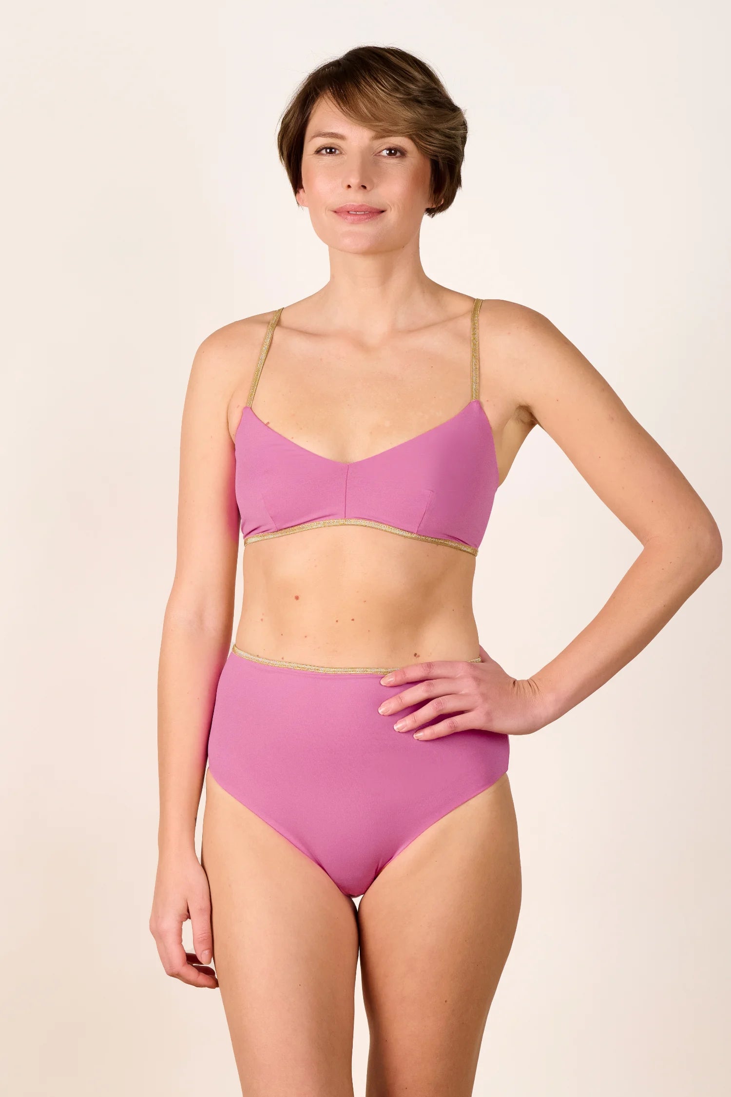 Frau trägt MYMARINI Bikini mit Spaghettiträgern und High-Waist-Schnitt in Rosa.#color_bronze-orchid
