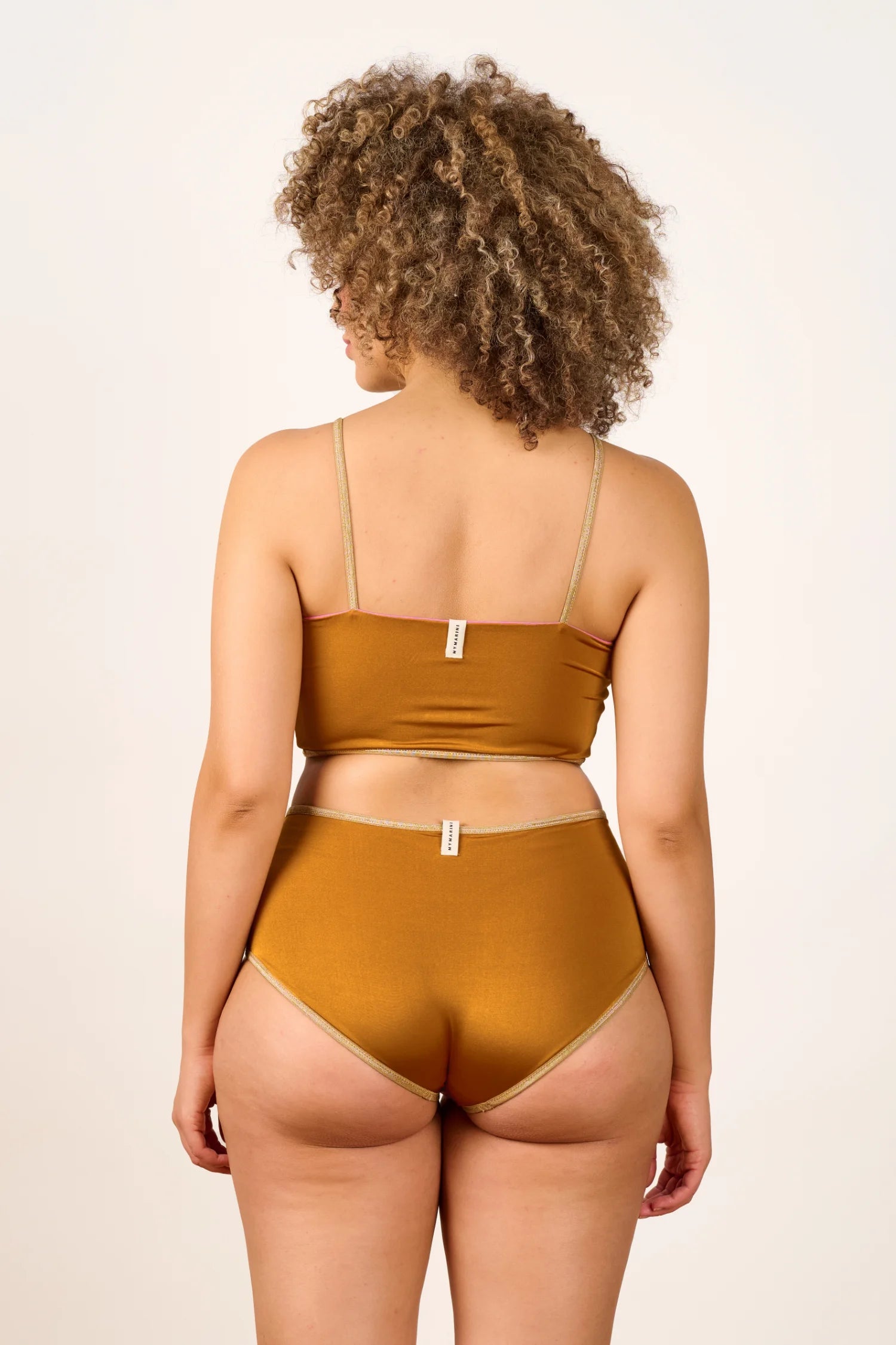 Person trägt MYMARINI Bikini mit Bandeau-Top und High-Waist-Hose in Braun, Rückansicht.#color_bronze-orchid