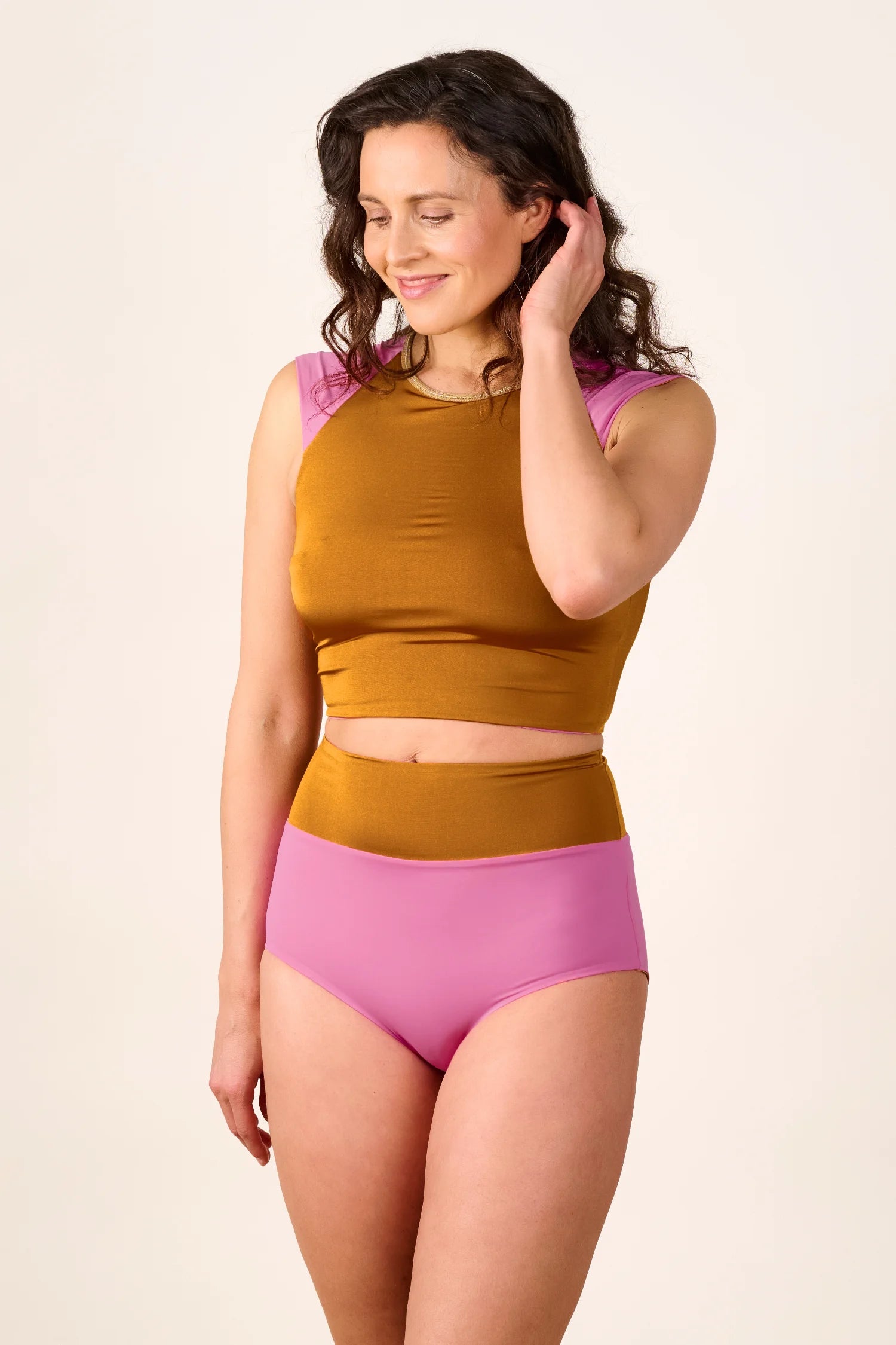 Frau trägt MYMARINI Bikini mit hochgeschlossenem Top und High-Waist-Hose in Braun und Rosa.#color_bronze-orchid