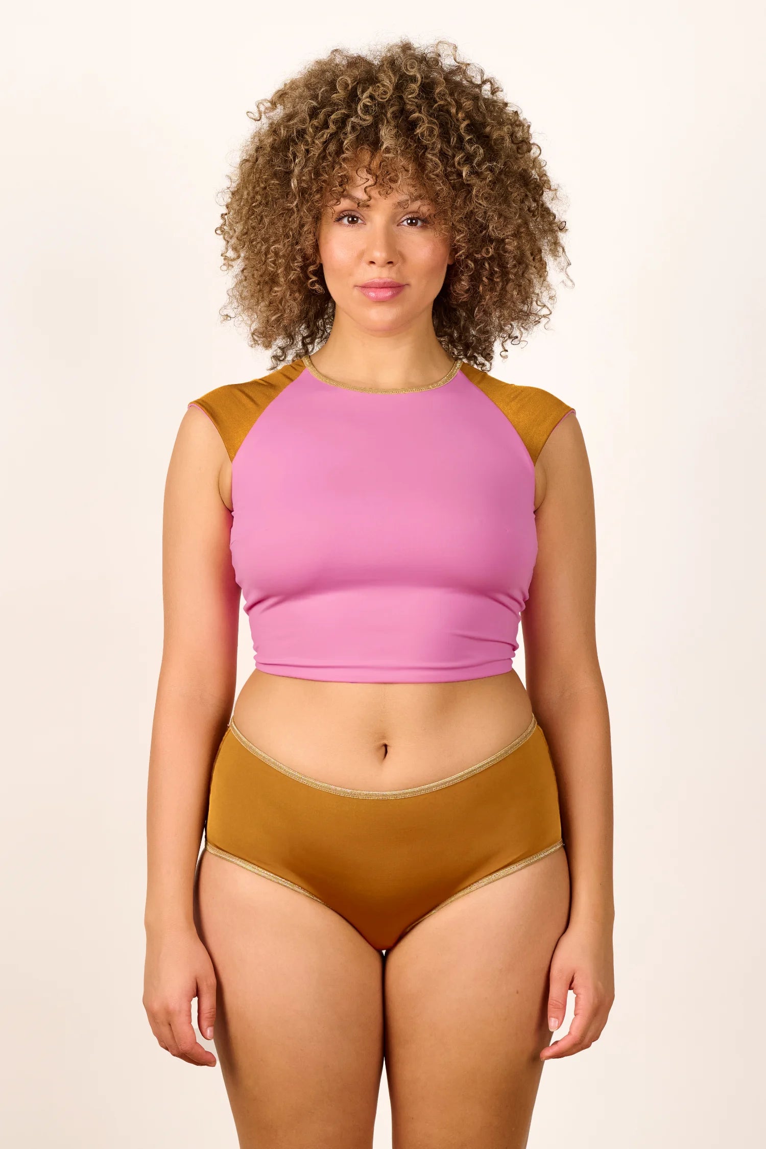 Frau trägt MYMARINI Badeanzug mit hochgeschlossenem Top in Rosa und Bikinihose in Braun, beide mit breiten Trägern.#color_bronze-orchid