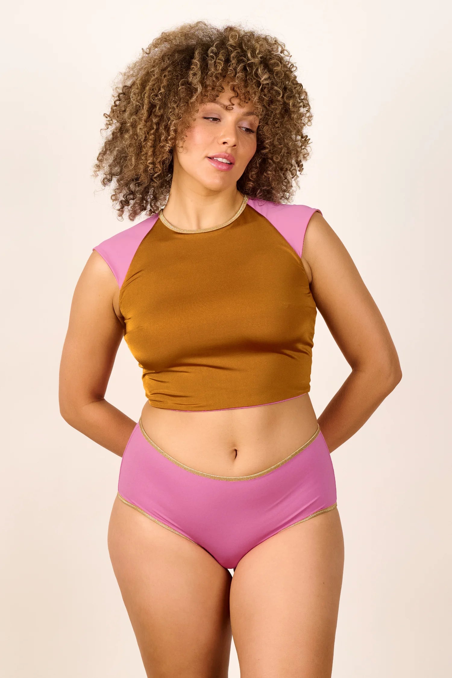 Frau trägt MYMARINI Bikinitop mit Rundhalsausschnitt und Bikinihose in Rosa und Braun.#color_bronze-orchid