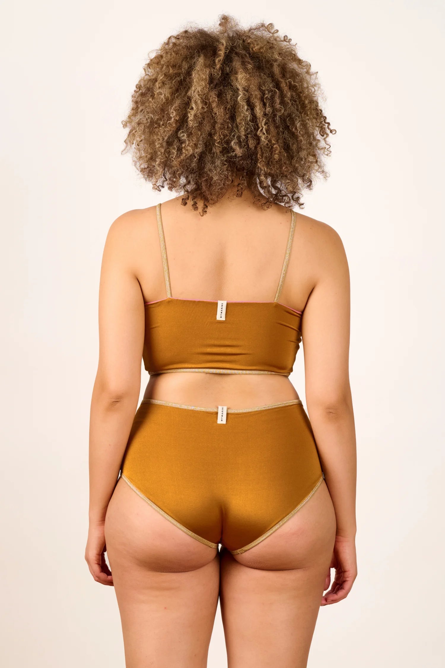 Rückansicht einer Person in MYMARINI-Bikini mit Spaghettiträgern und High-Waist-Schnitt in Goldbraun.#color_bronze-orchid