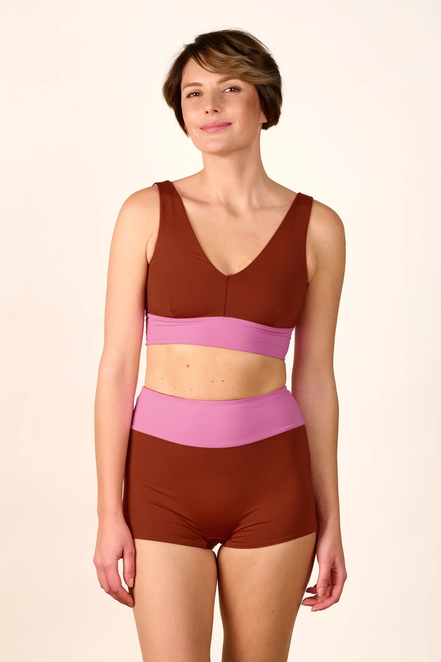 Frau trägt MYMARINI Bikini mit V-Ausschnitt und High Waist in Braun und Rosa.#color_sienna-orchid