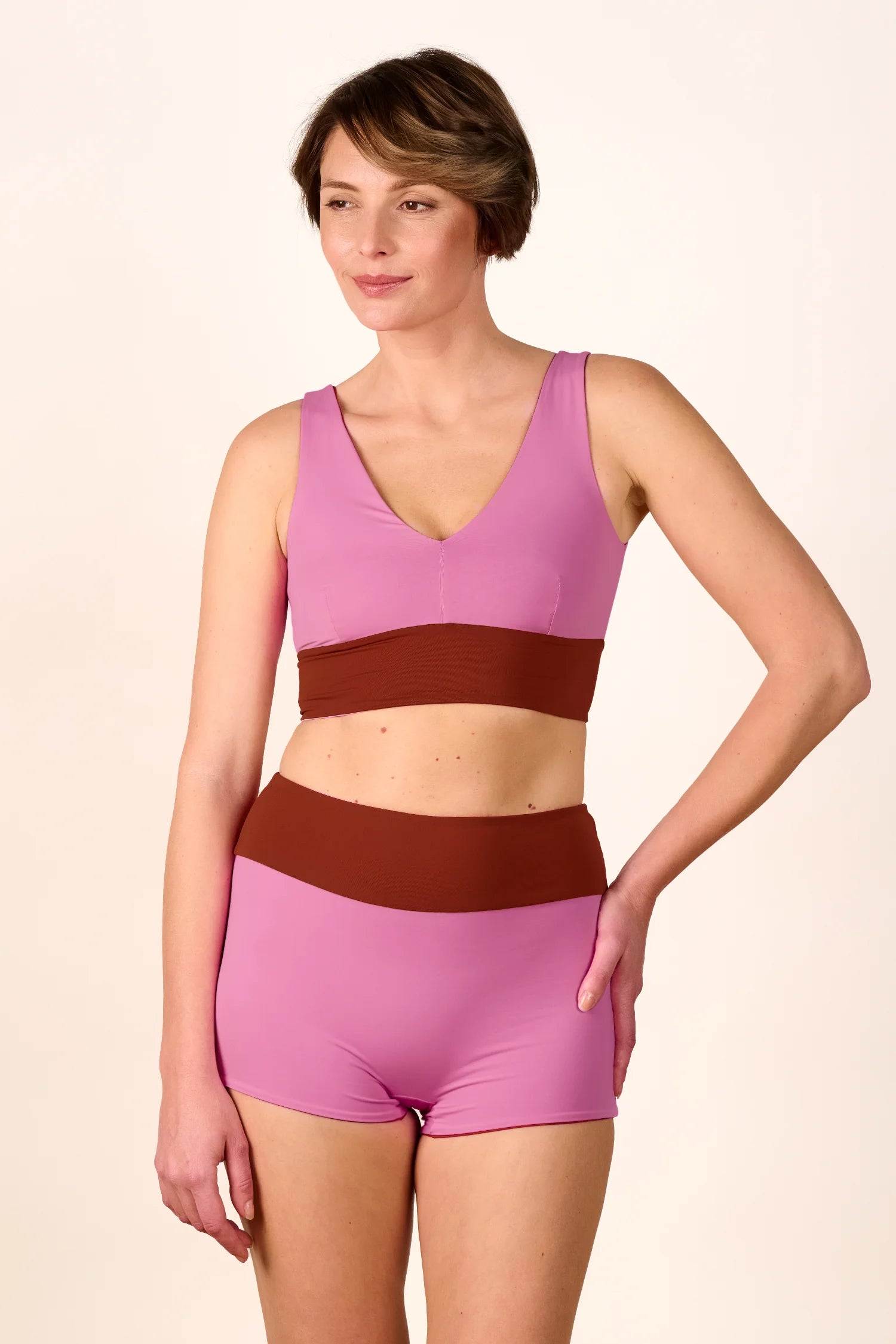 Frau trägt MYMARINI Bikinitop mit V-Ausschnitt und Bikinihose mit hohem Bund in Rosa und Braun.#color_sienna-orchid