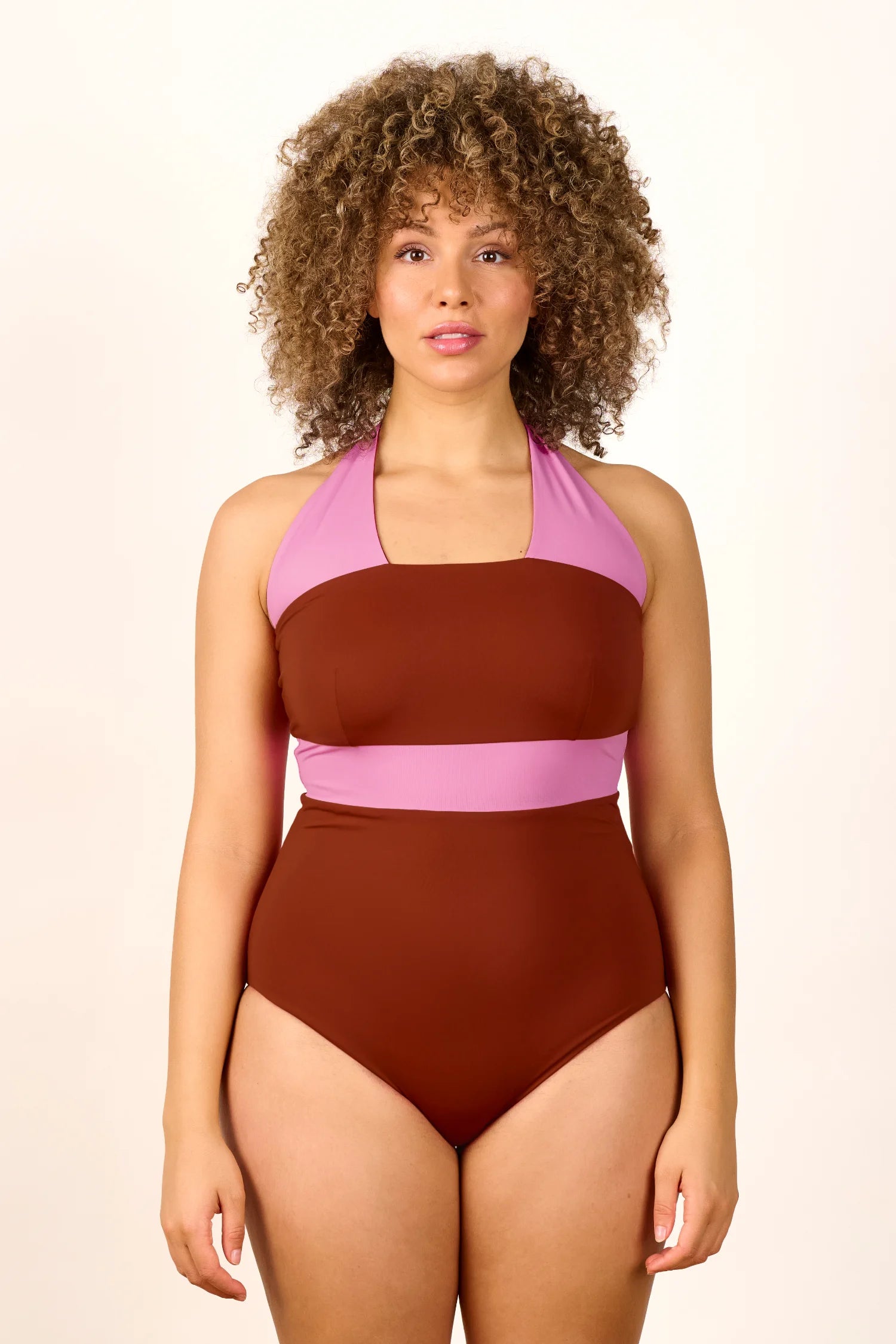 Frau trägt MYMARINI One-Piece Badeanzug in Braun und Rosa mit Neckholder und hohem Beinausschnitt.#color_sienna-orchid