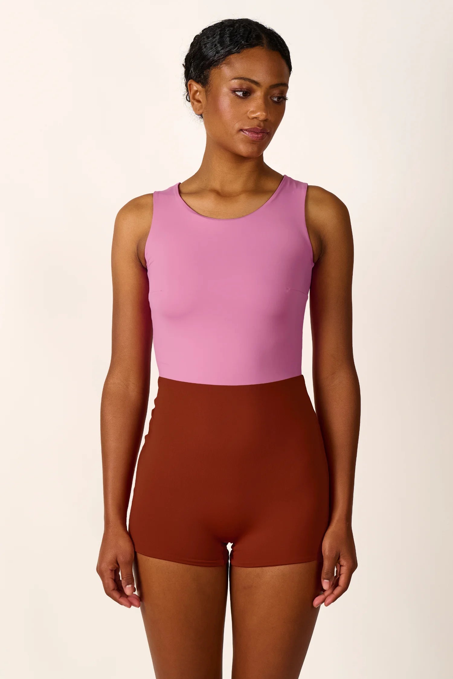 Person trägt einen MYMARINI One-Piece Badeanzug in Rosa und Braun, hoch geschlossen, mit breiten Trägern.#color_sienna-orchid