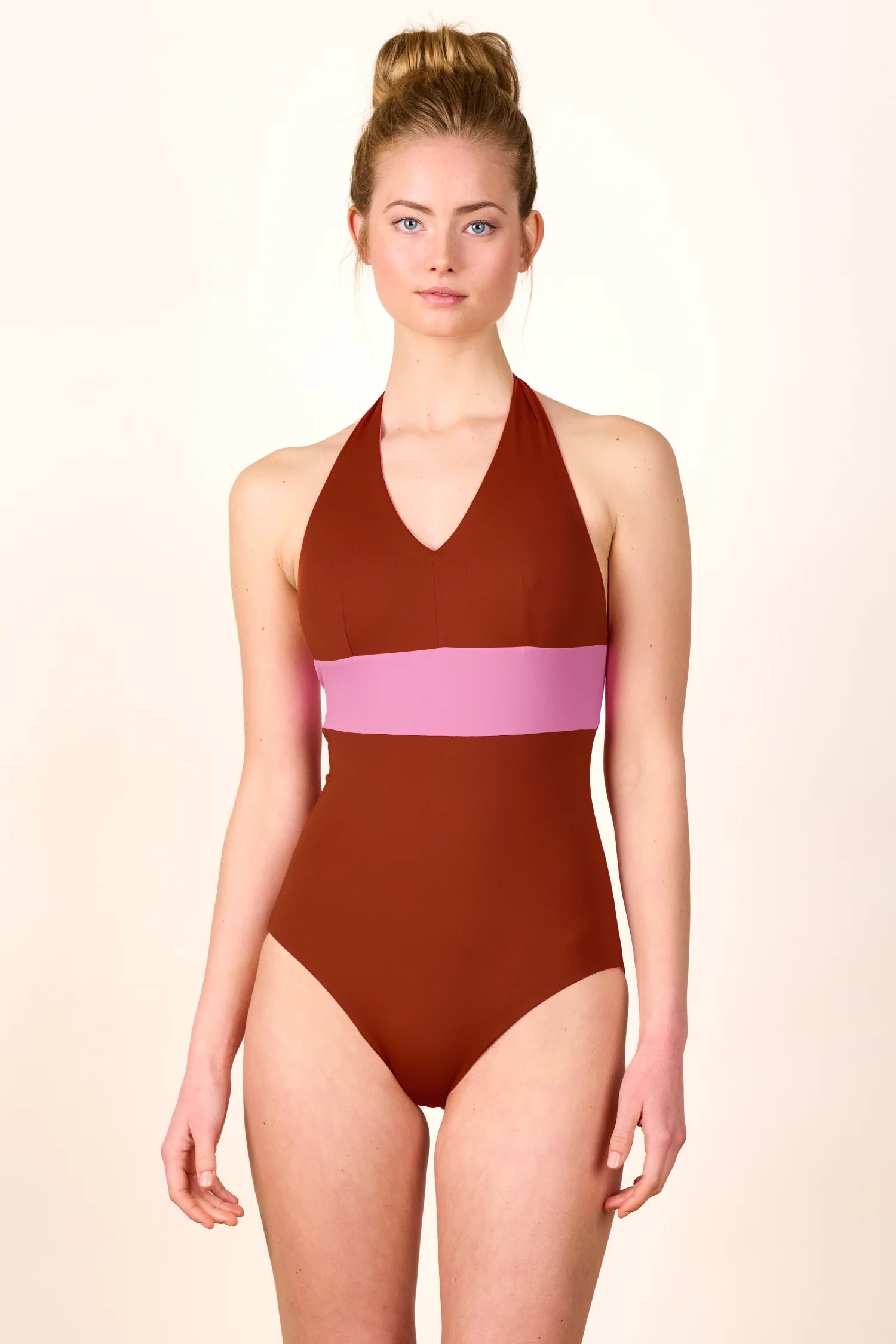 Frau trägt MYMARINI One-Piece mit Neckholder und V-Ausschnitt in Braun und Rosa.#color_sienna-orchid