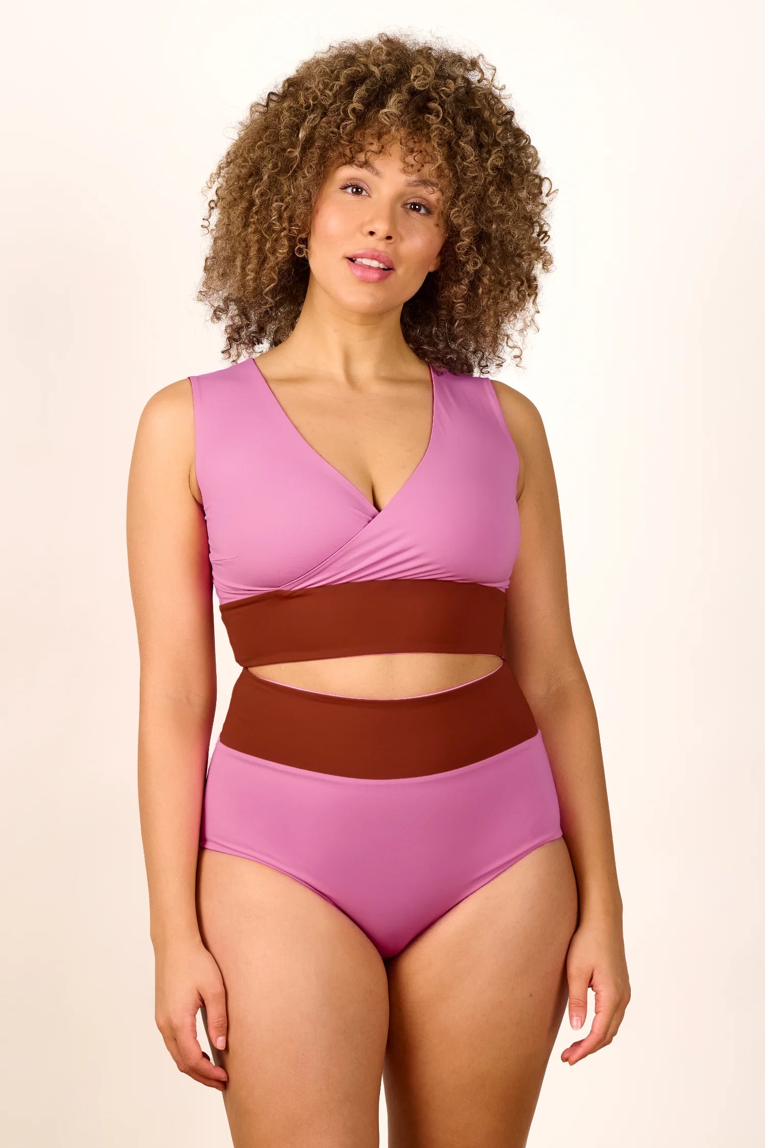 Frau trägt MYMARINI Badeanzug mit V-Ausschnitt und hohem Beinausschnitt in Rosa und Braun.#color_sienna-orchid