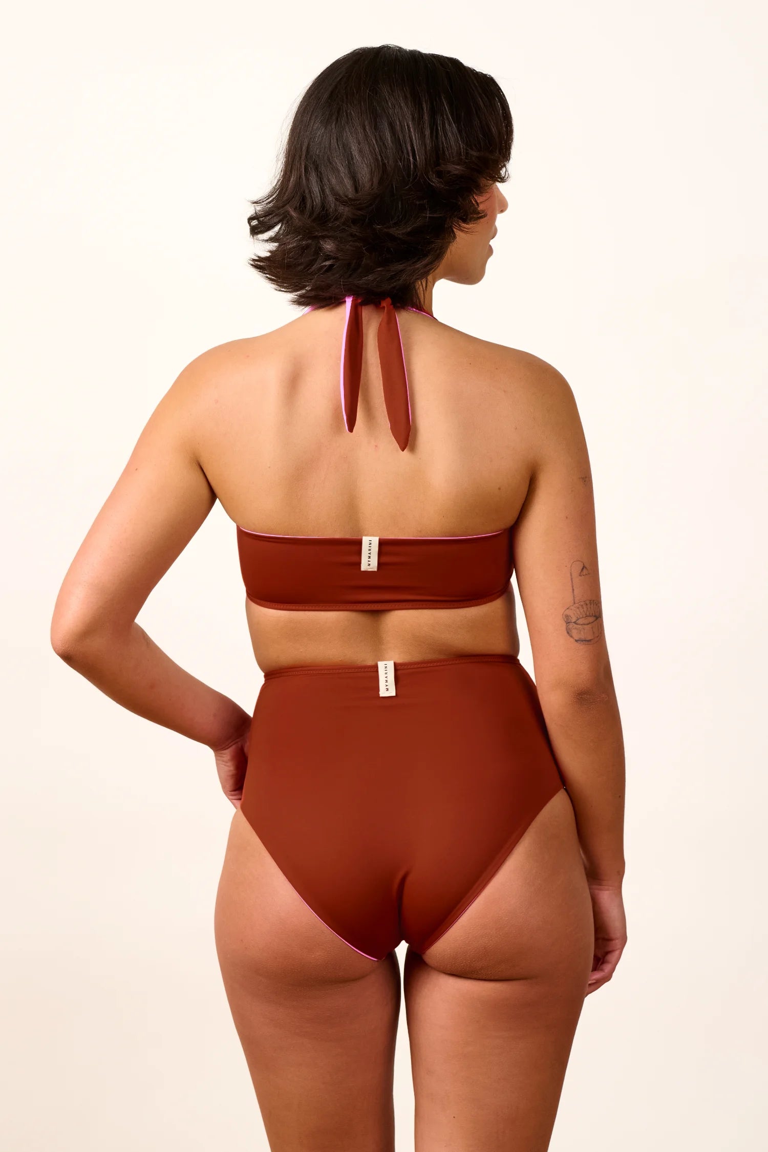 Frau in MYMARINI Bikini mit Neckholder-Top und High-Waist-Hose in Rot, von hinten gezeigt.#color_sienna-orchid