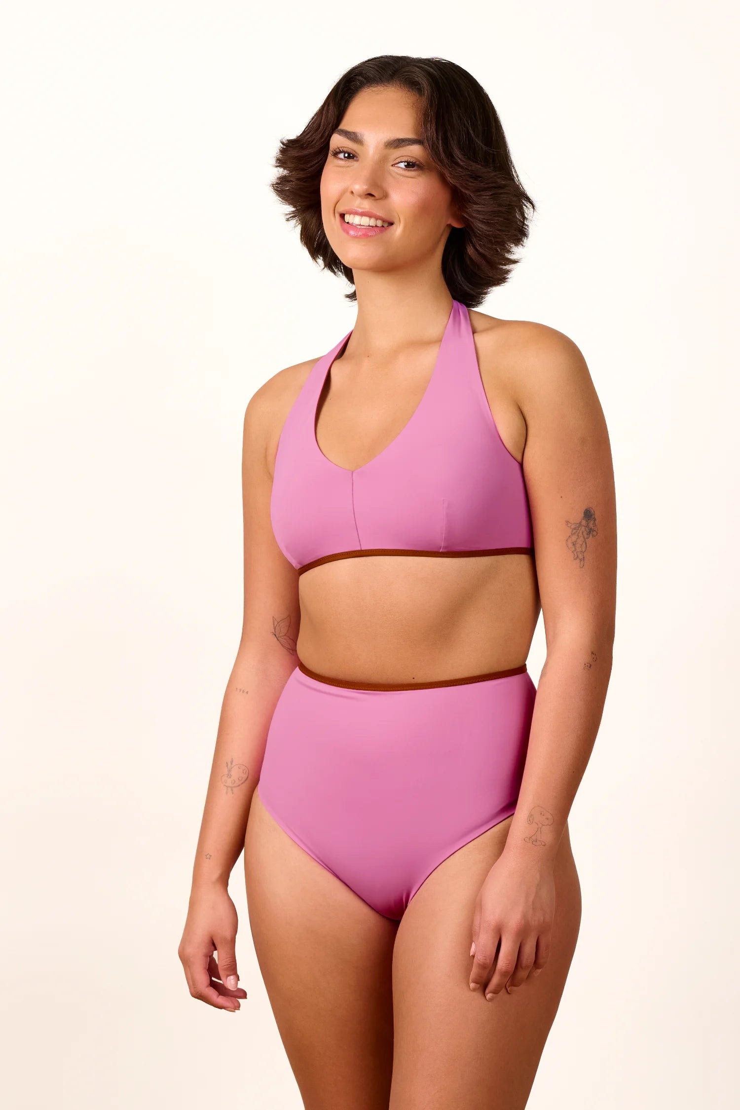 Frau trägt MYMARINI Bikini mit hochgeschlossenem Bikinitop und High-Waist-Bikinihose in Rosa, lächelnd vor hellem Hintergrund.#color_sienna-orchid