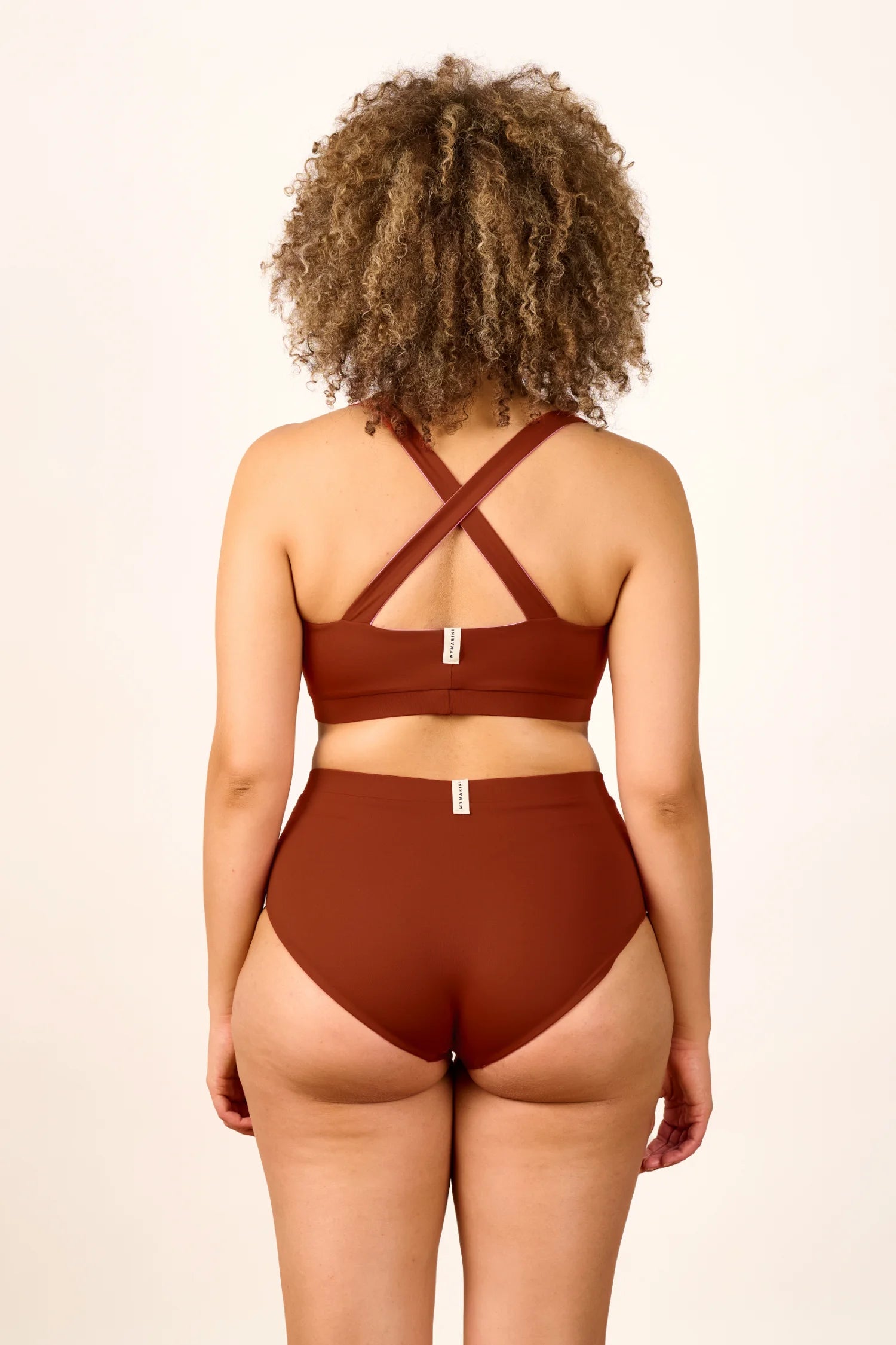 Person trägt MYMARINI Bikini mit Cross Top und High Waist in Braun, Rückansicht.#color_sienna-orchid