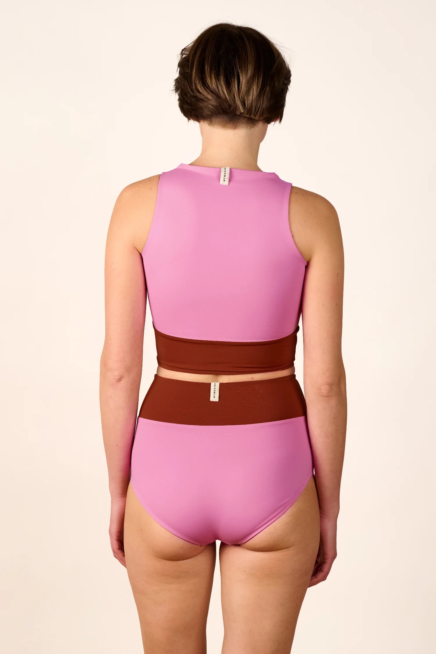 Person von hinten in MYMARINI Bikinihose und Bikinitop. Hoch geschlossenes Top, Mid rise Hose, zweifarbig in Rosa und Braun.#color_sienna-orchid