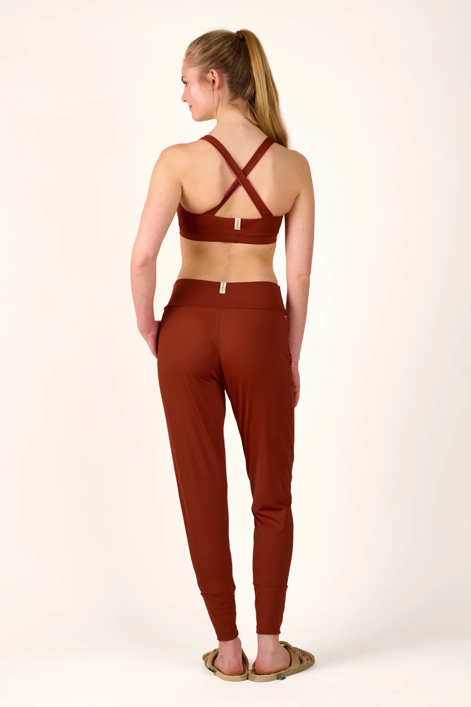 Frau in MYMARINI Cross Top und Hose in Braun, von hinten.#color_sienna