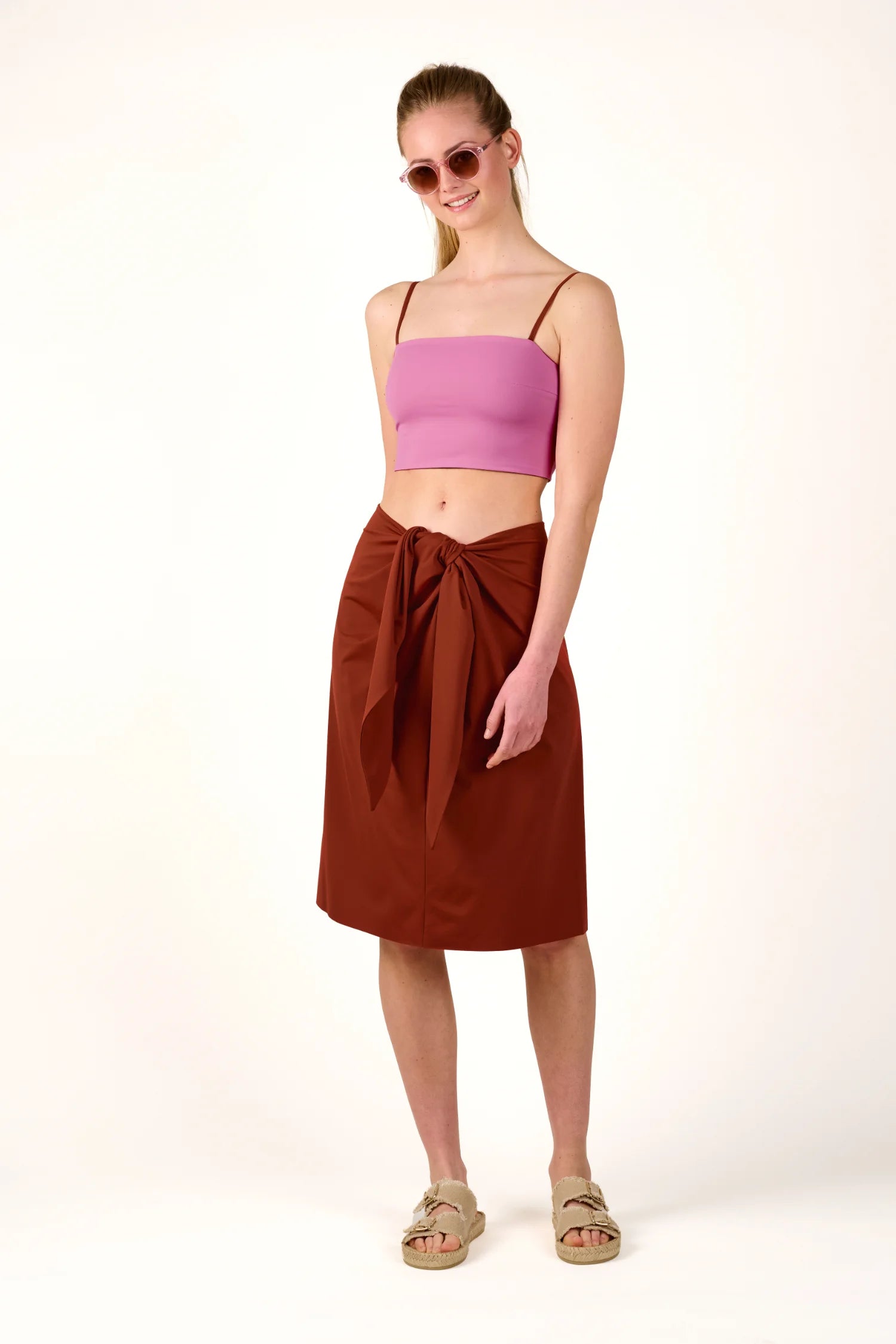 Person trägt ein MYMARINI Bikinitop mit Spaghettiträgern und einen braunen Rock.#color_sienna