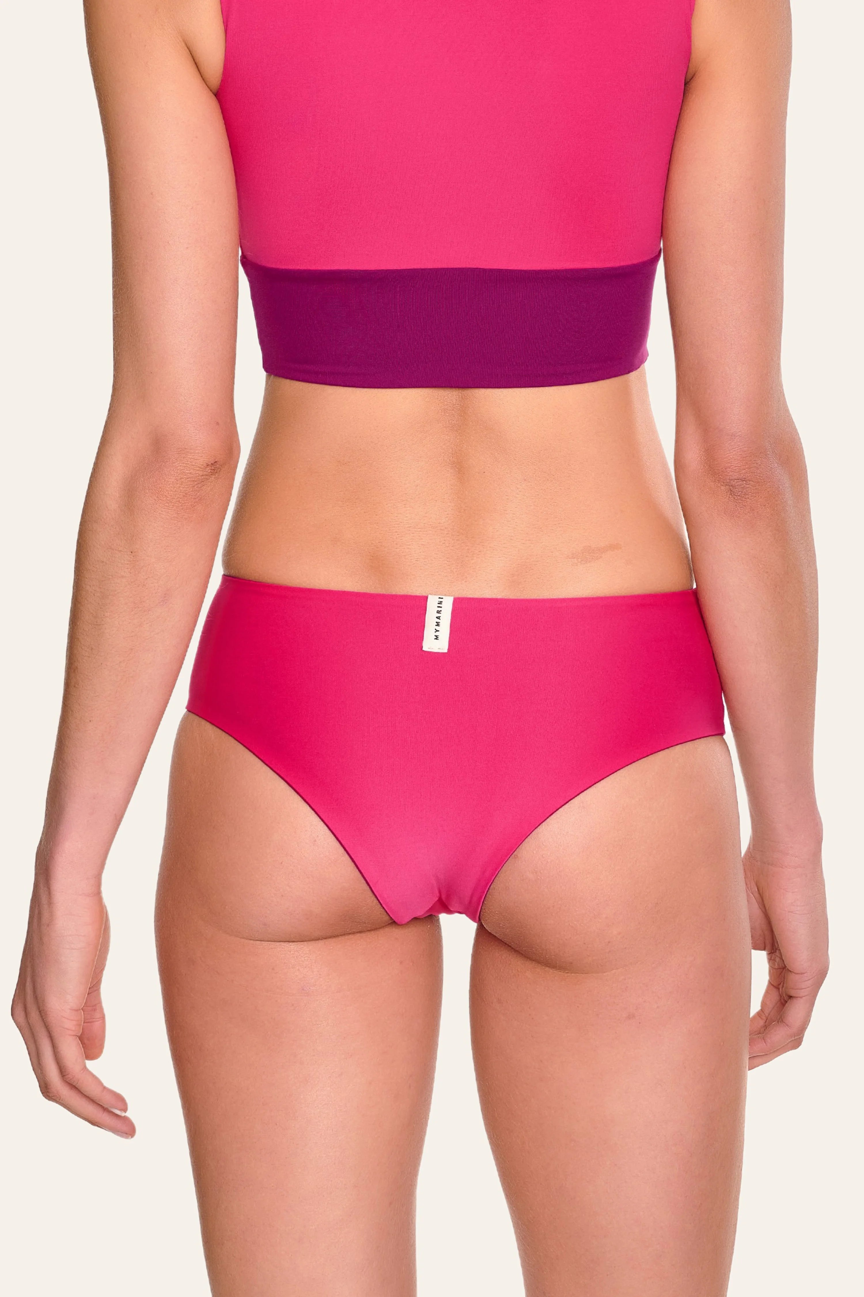 Rückansicht einer Person in pinker MYMARINI Bikinihose mit hohem Beinausschnitt.#color_pink-hortensia