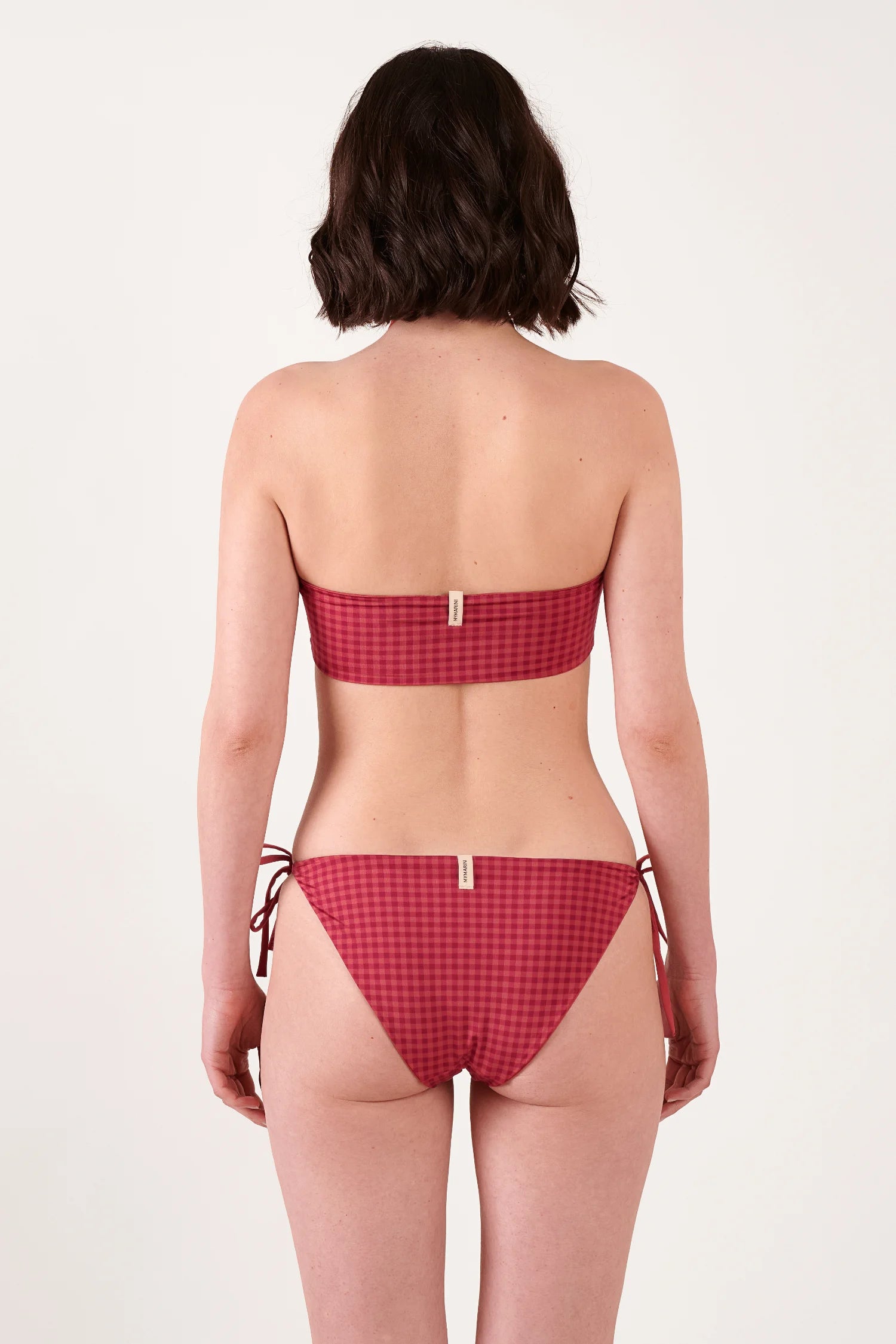 Rückenansicht einer Person in Karobikini: Bandeau-Bikinitop und Bikinihose mit Seitenträgern, MYMARINI-Label sichtbar.#color_rouge-vichy