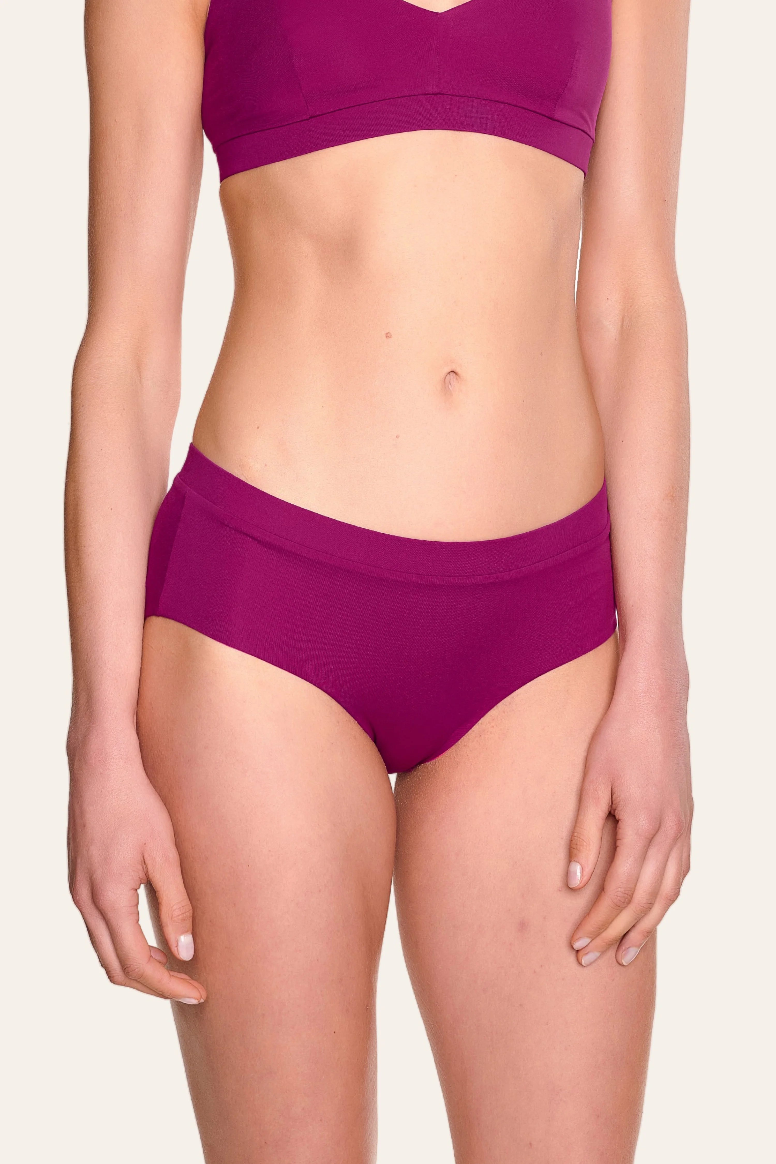 Frau trägt MYMARINI Bikinihose in Lila, Mid rise, mit passendem Bikinitop.#color_pink-hortensia