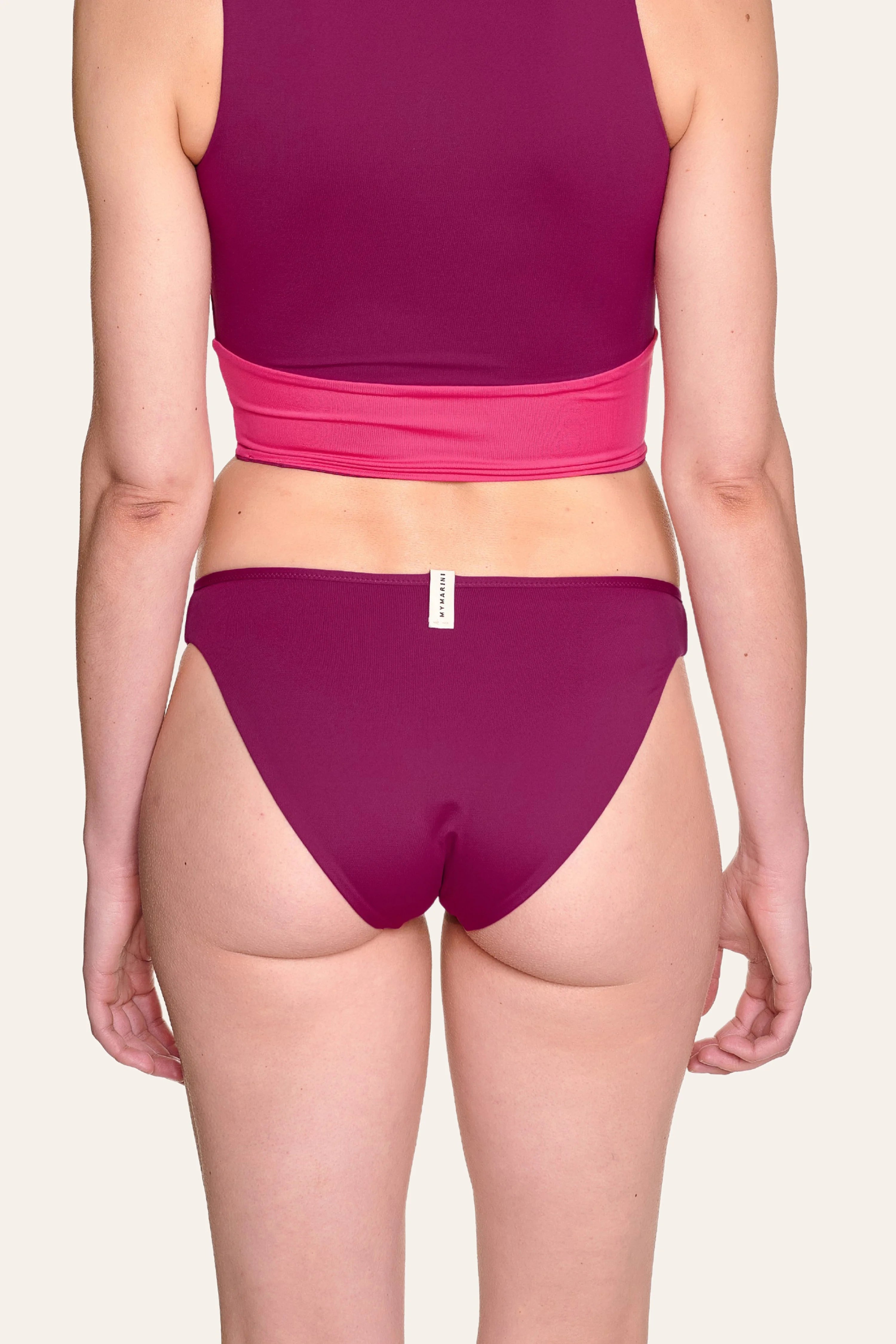 Rückansicht einer Person in MYMARINI Bikinihose mit hohem Beinausschnitt in Magenta.#color_pink-hortensia
