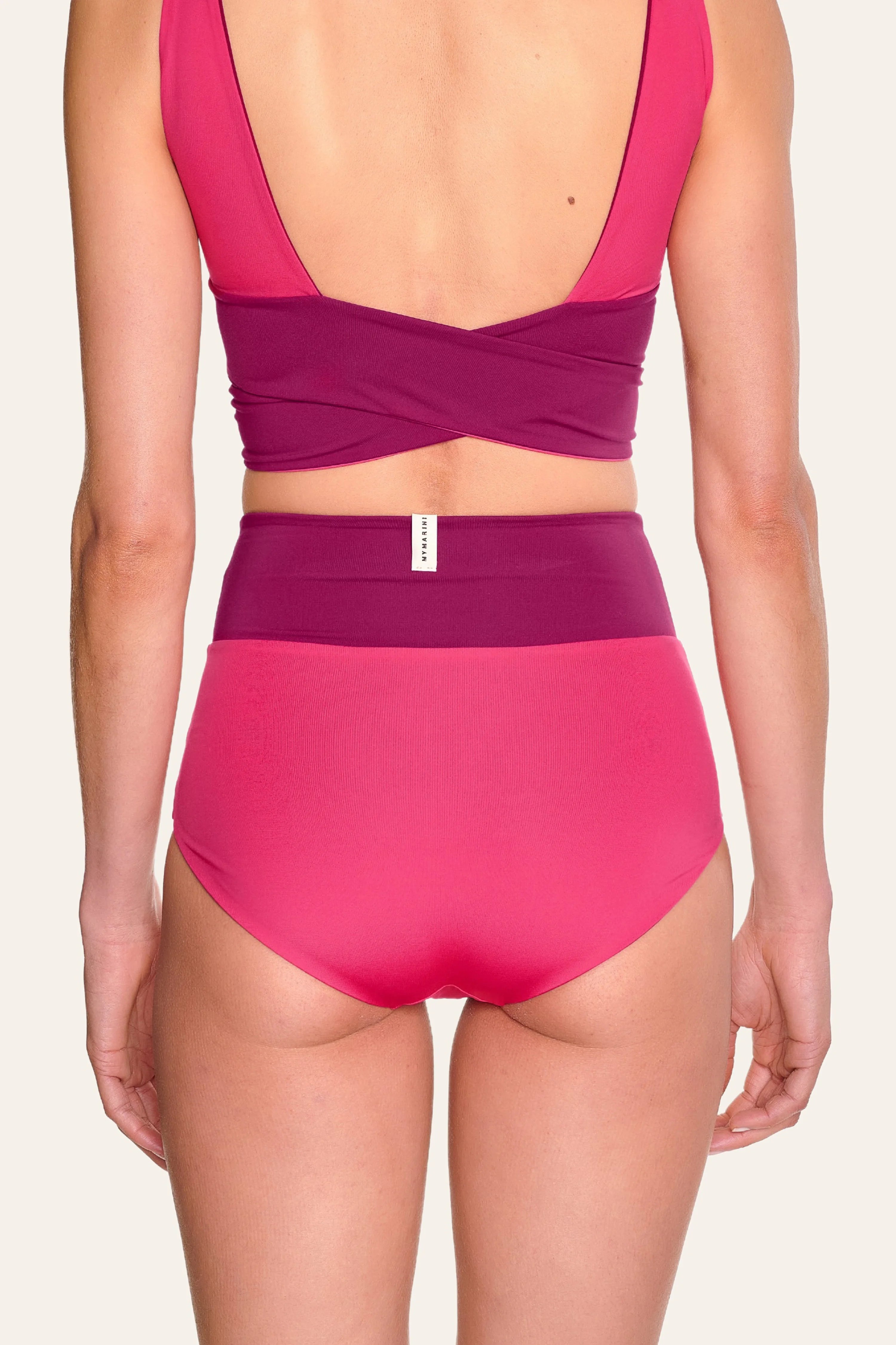 Rückansicht einer Frau in einem MYMARINI Bikinitop mit tiefem Rückenausschnitt und einer High-Waist-Bikinihose in Pink.#color_pink-hortensia
