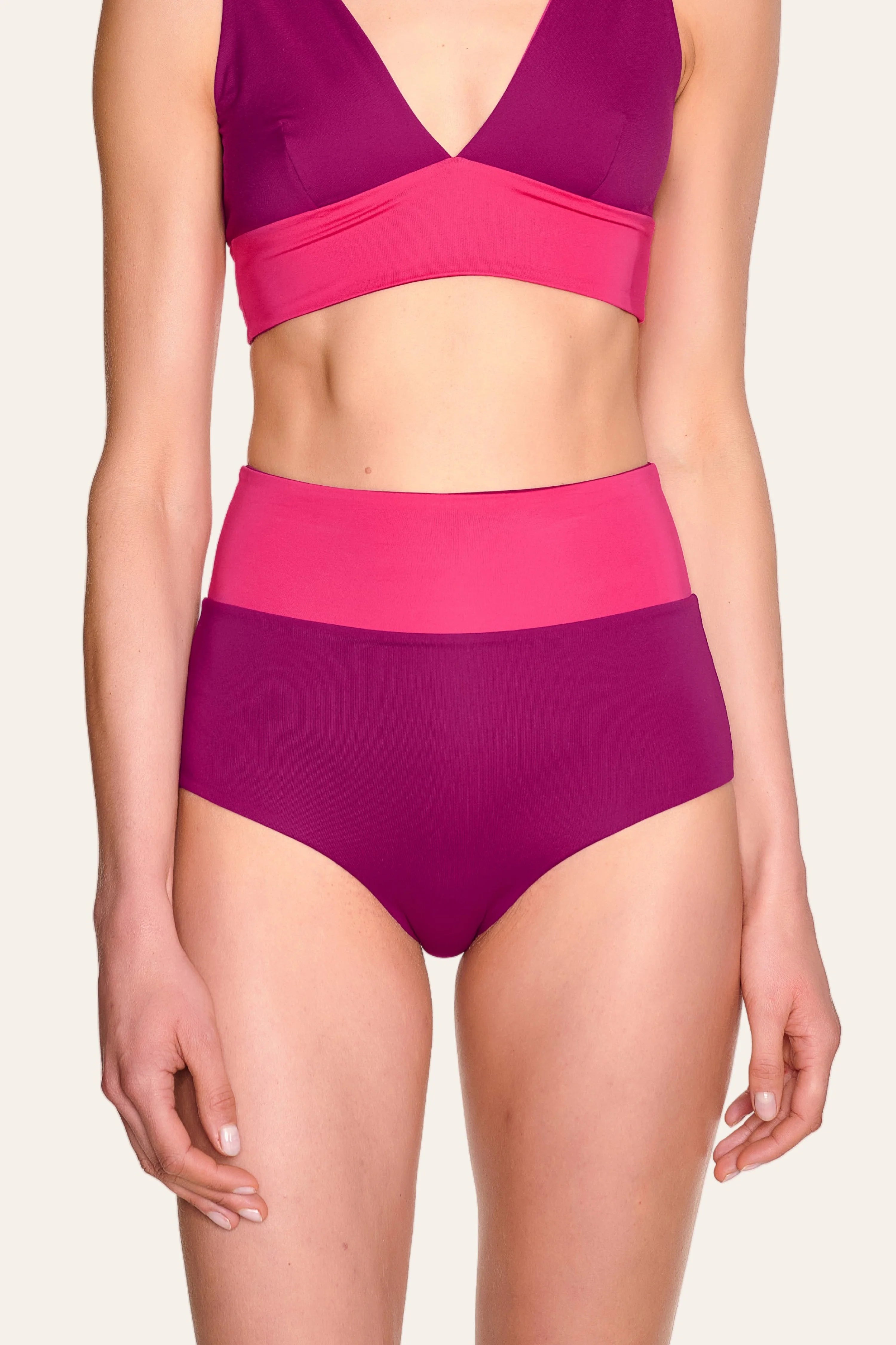 Frau trägt MYMARINI Bikini mit V-Ausschnitt und High-Waist-Hose in Pink- und Violetttönen.#color_pink-hortensia