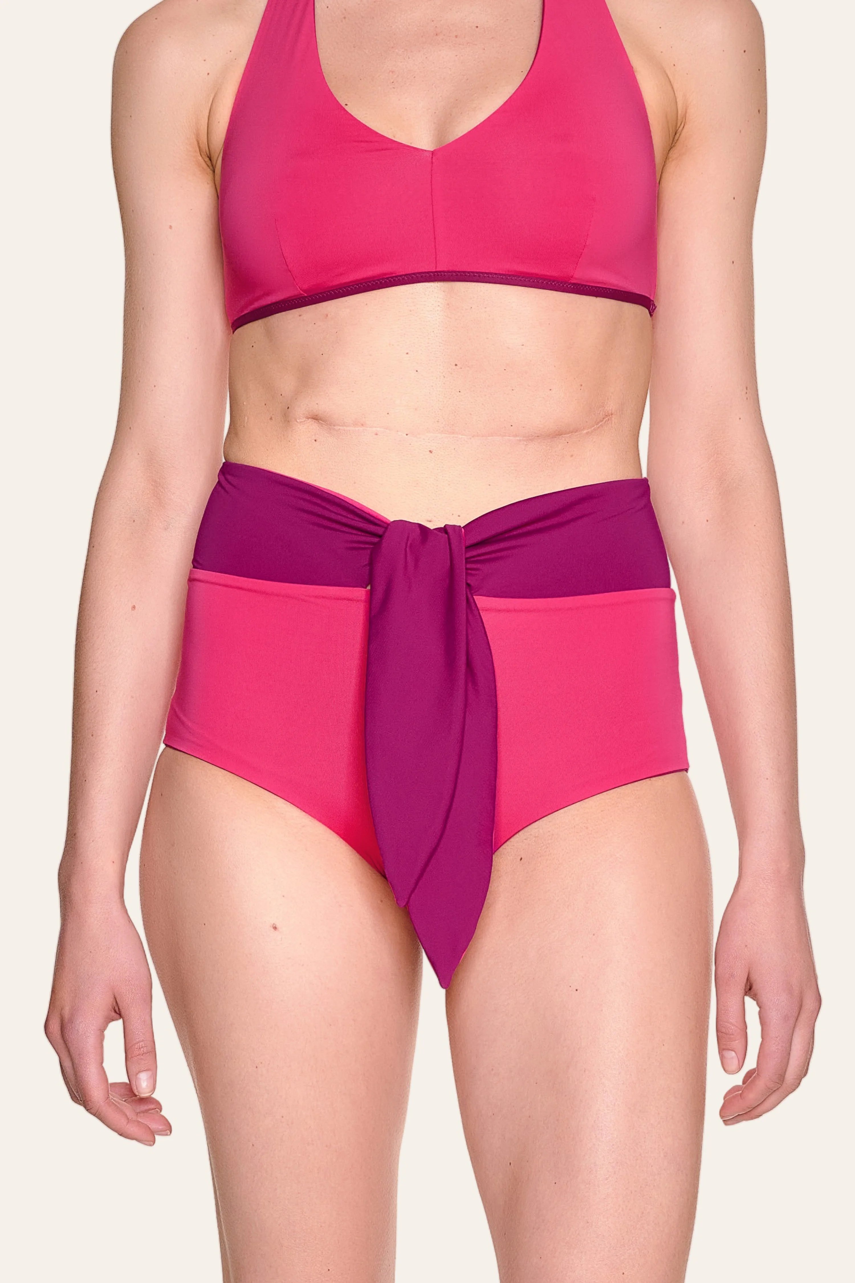 Frau trägt MYMARINI Bikini mit V-Ausschnitt und High-Waist-Hose in Pink und Lila.#color_pink-hortensia