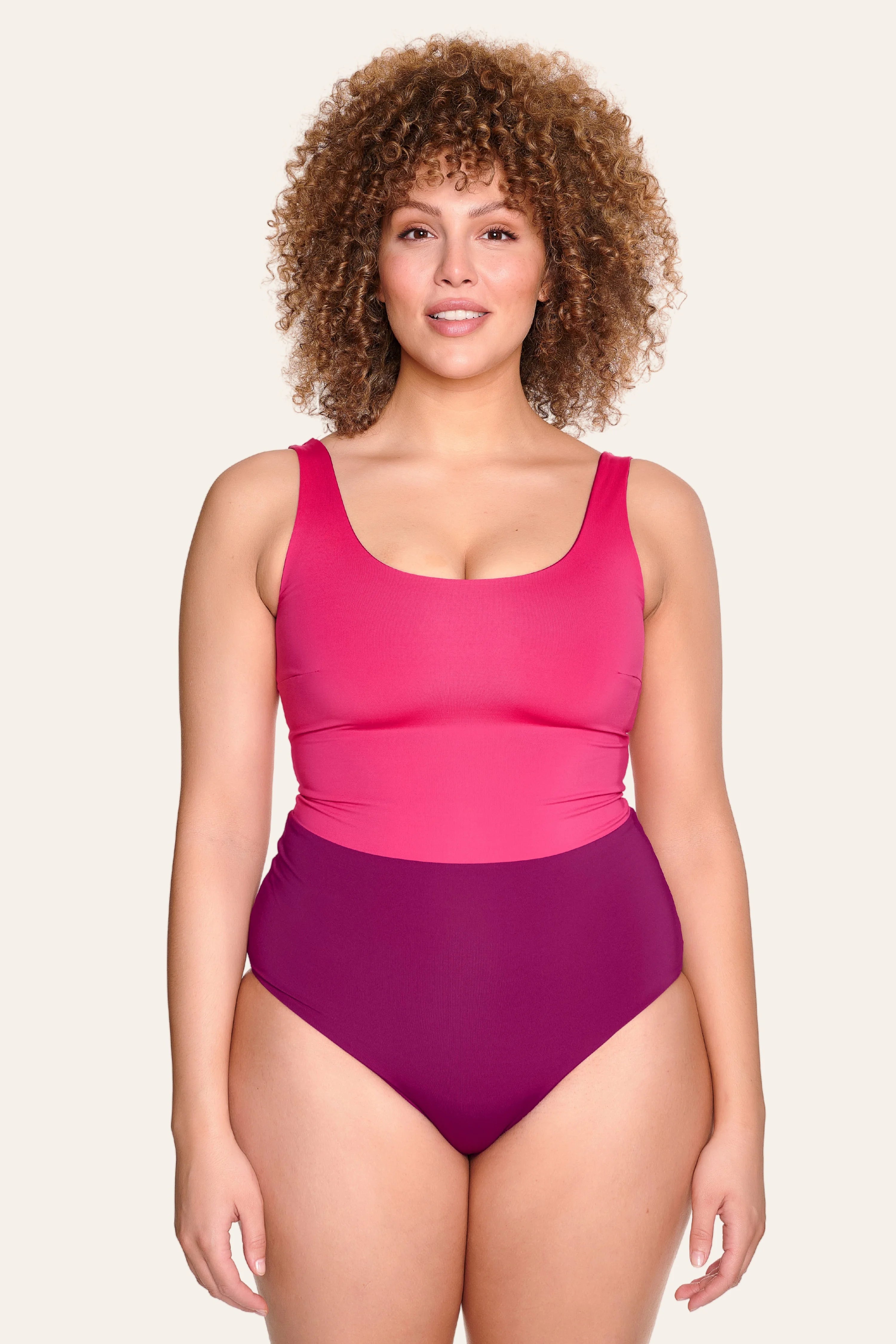 Frau trägt MYMARINI Badeanzug mit breiten Trägern und hohem Beinausschnitt in Pink- und Violetttönen.#color_pink-hortensia