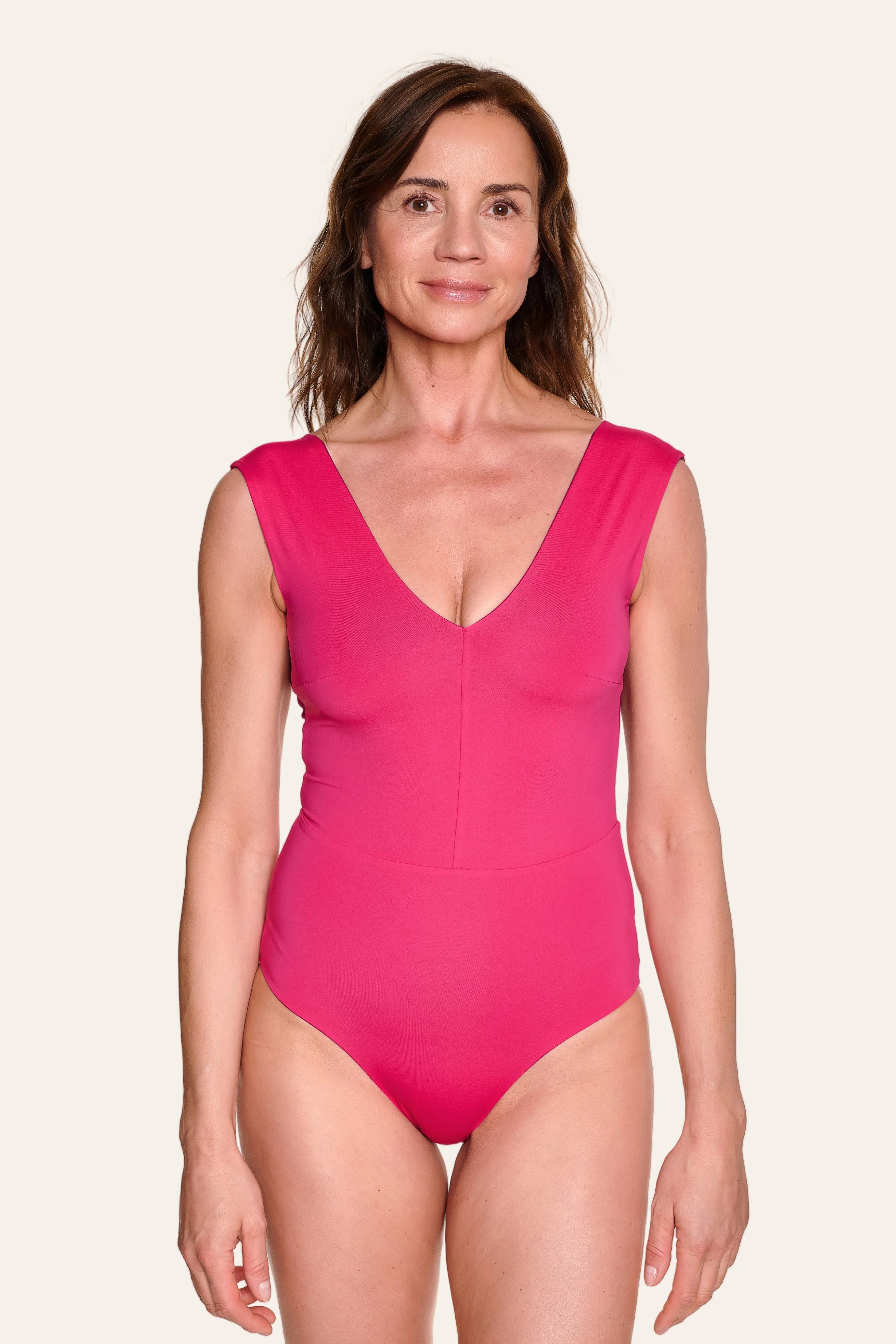 Frau trägt pinken MYMARINI Badeanzug mit V-Ausschnitt und breiten Trägern.#color_pink-hortensia