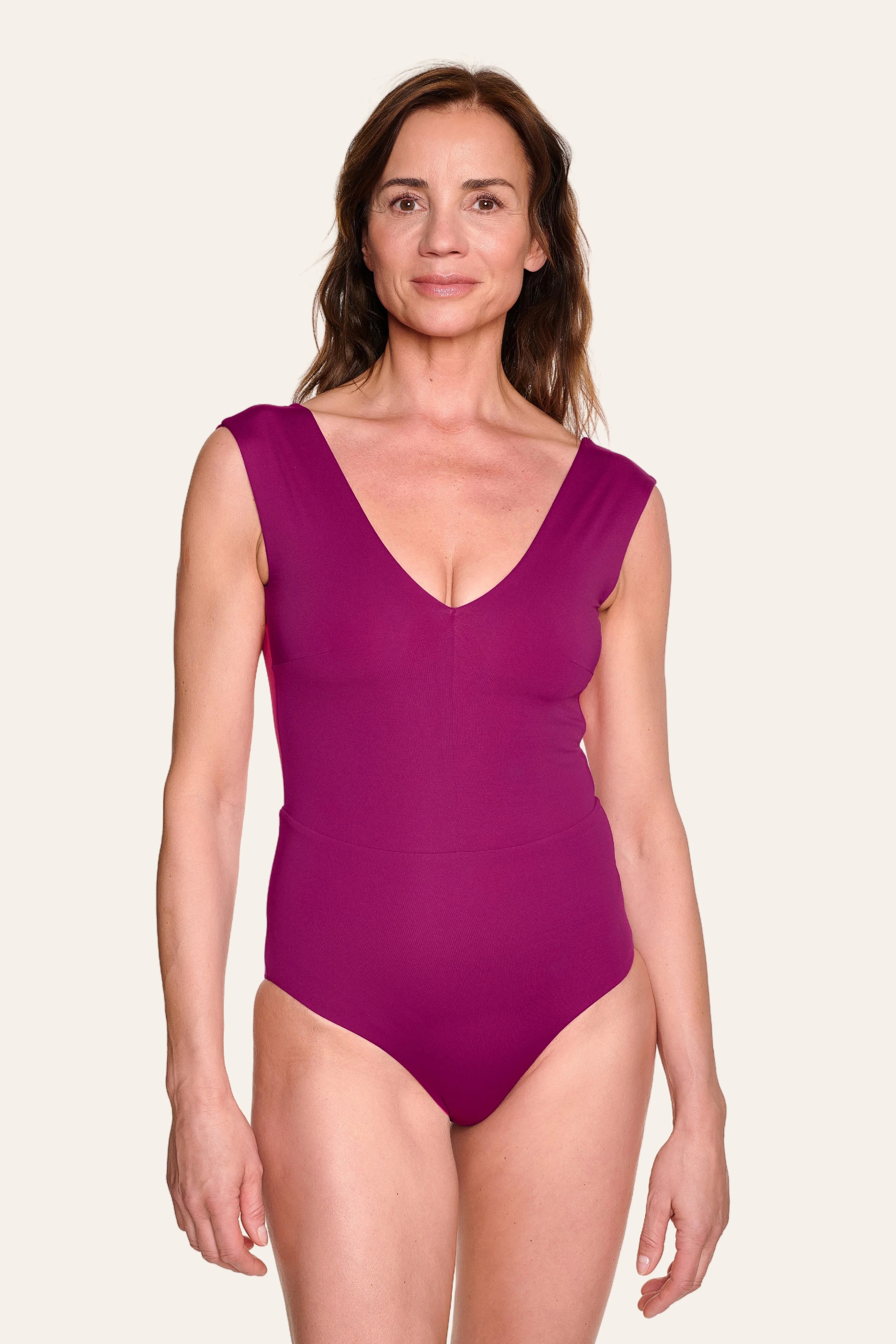 Frau trägt MYMARINI Badeanzug in Lila mit V-Ausschnitt und breiten Trägern.#color_pink-hortensia