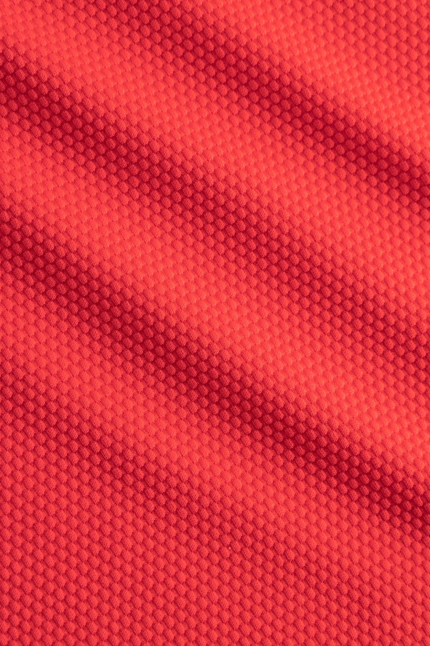 Nahaufnahme eines roten Textilgewebes mit feinem, regelmäßig geprägtem Muster und strukturierter Oberfläche.#color_rouge
