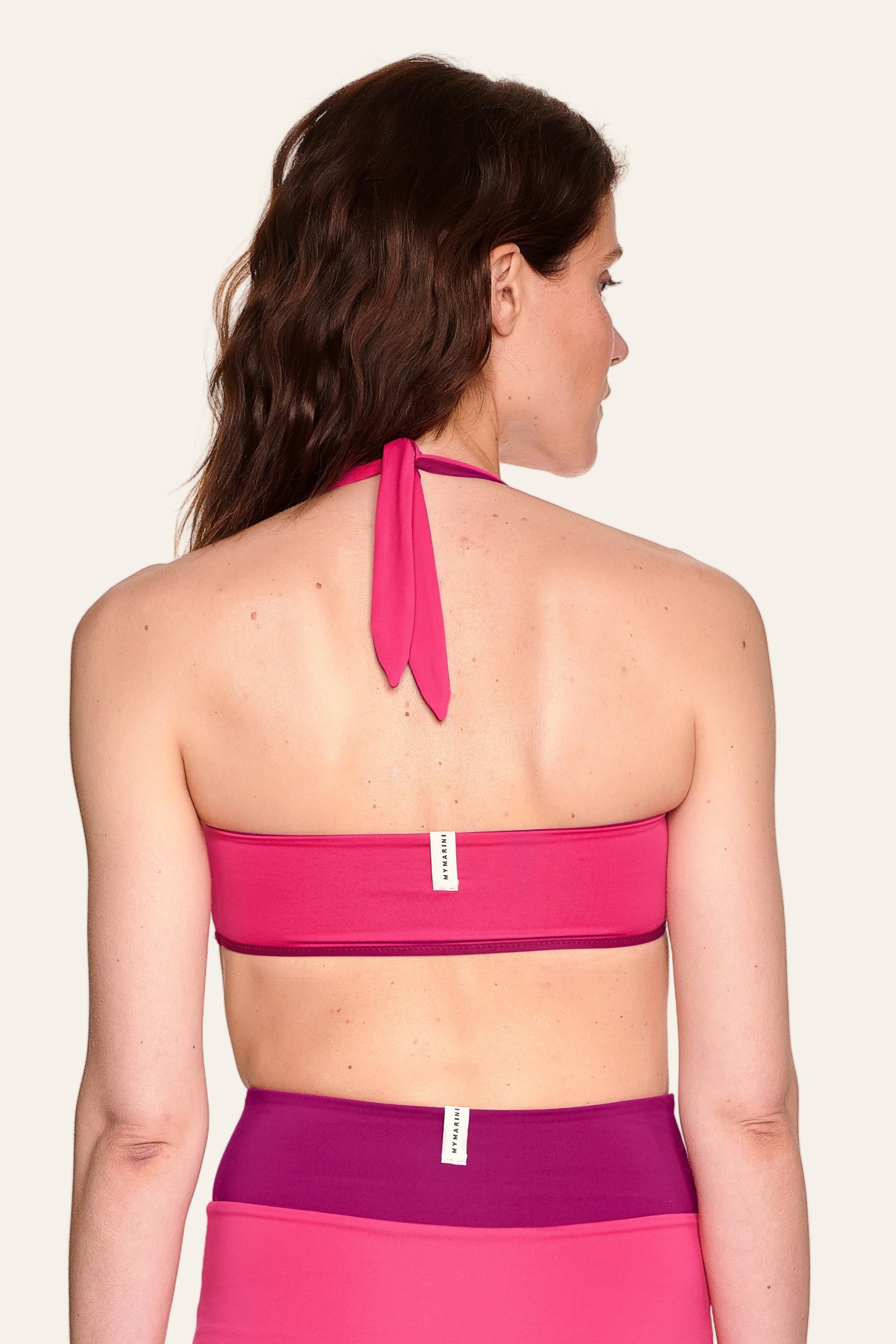 Frau von hinten in MYMARINI Neckholder-Bikinitop und High-Waist-Bikinihose in Pink und Lila.#color_pink-hortensia