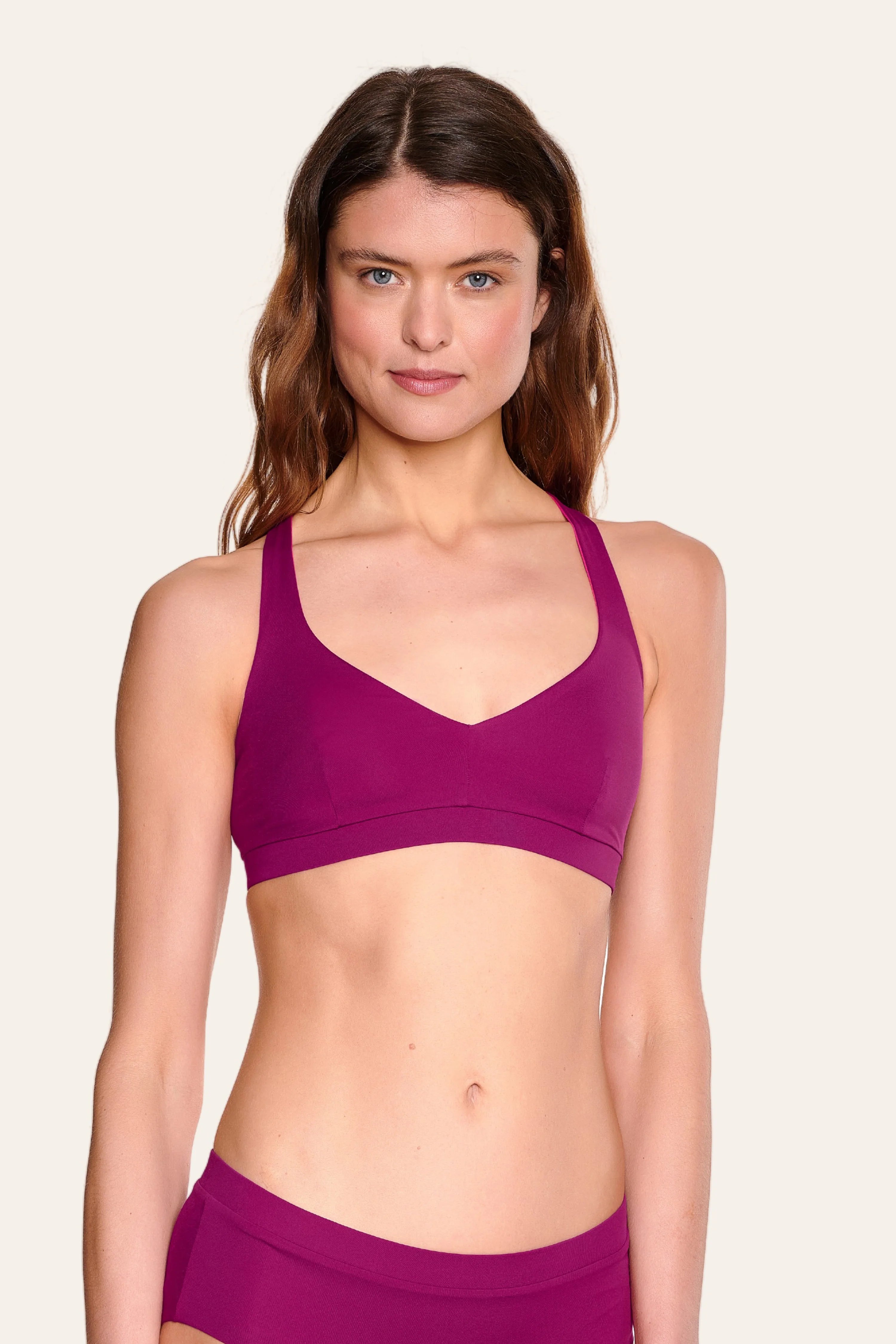 Frau trägt MYMARINI Bikinitop mit V-Ausschnitt und breiten Trägern in kräftigem Pink.#color_pink-hortensia