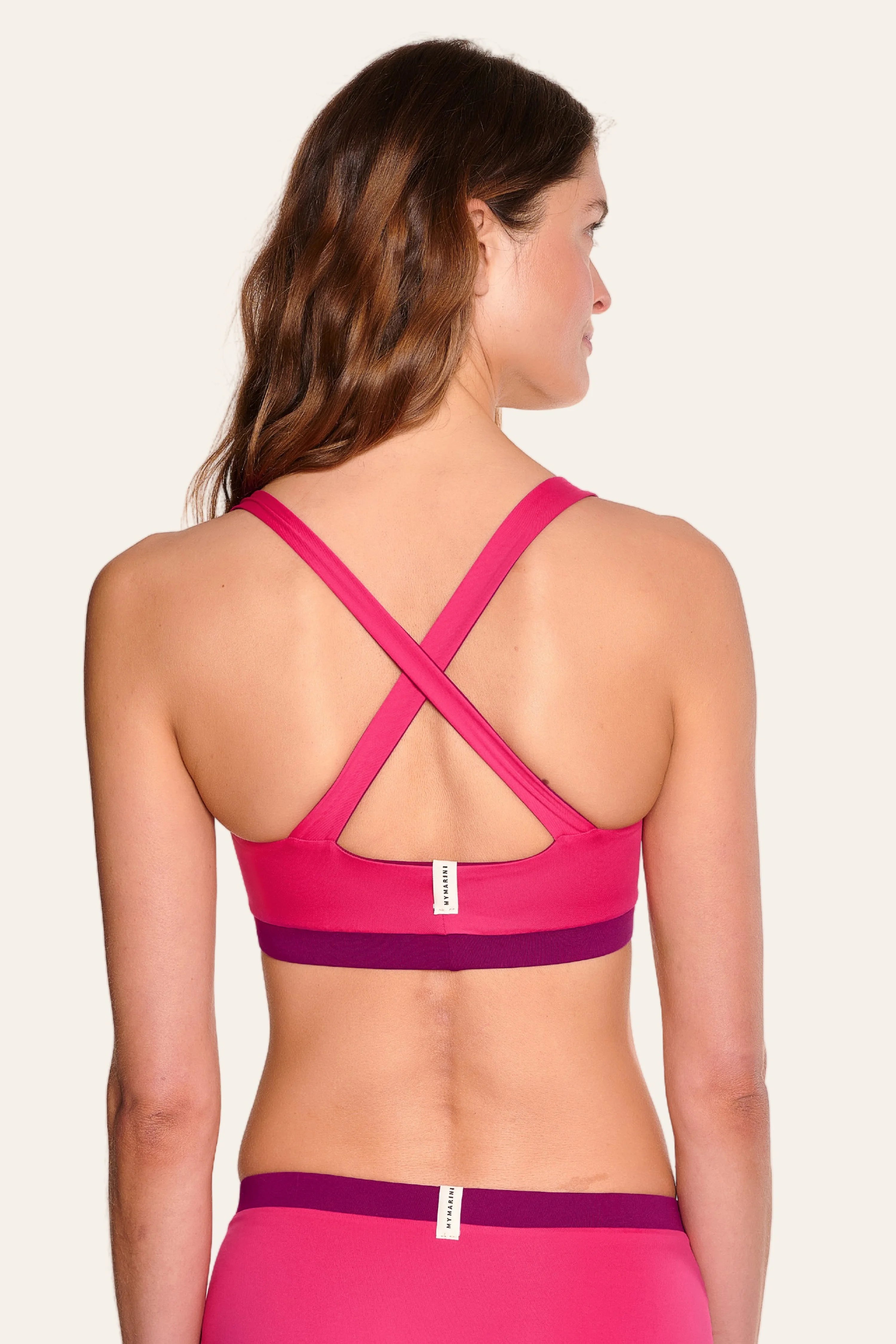 Frau von hinten in pinkem MYMARINI Bikinitop mit breiten, überkreuzten Trägern.#color_pink-hortensia