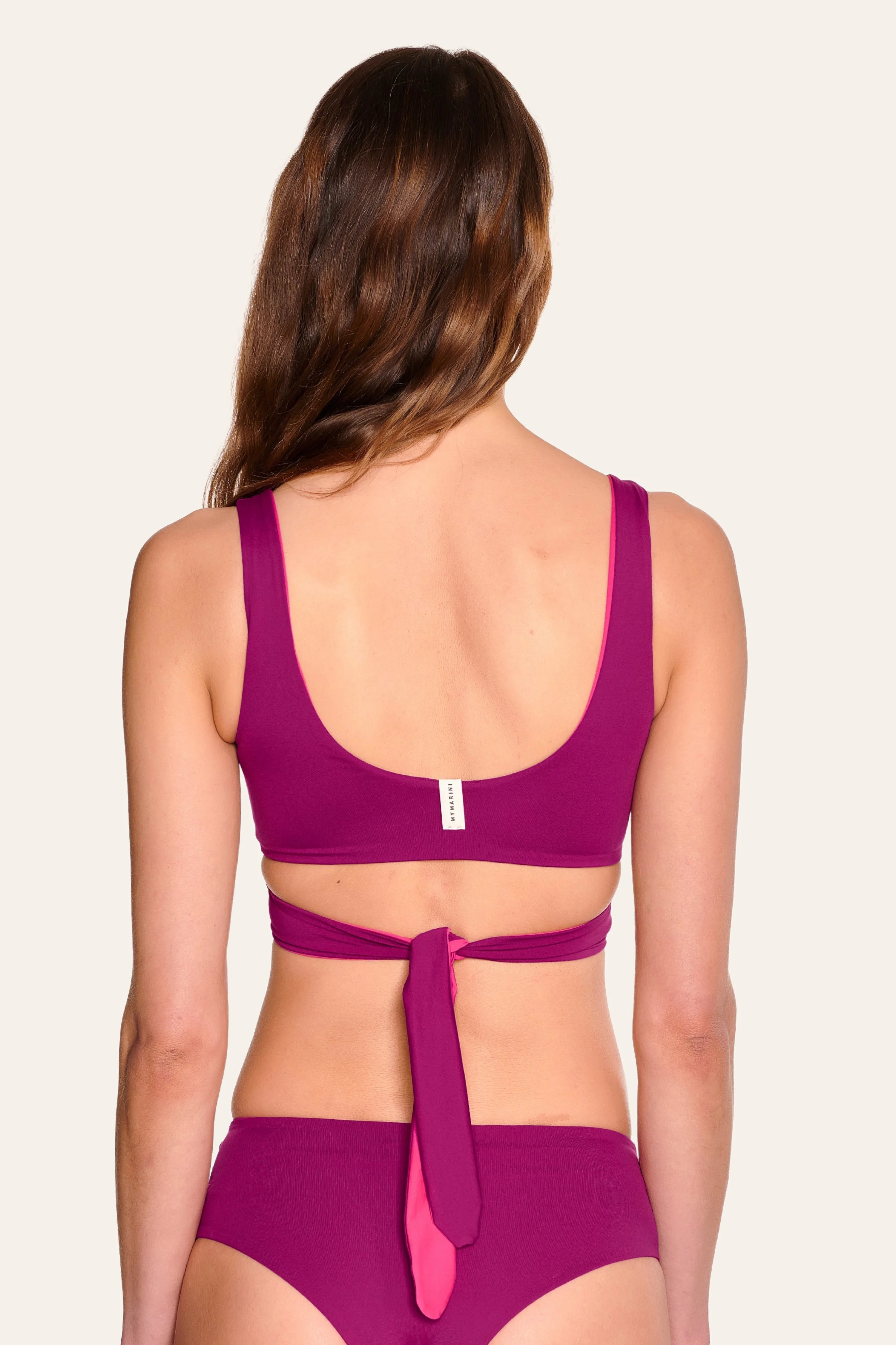 Frau in MYMARINI Bikini mit breiten Trägern und tiefem Rückenausschnitt, von hinten.#color_pink-hortensia
