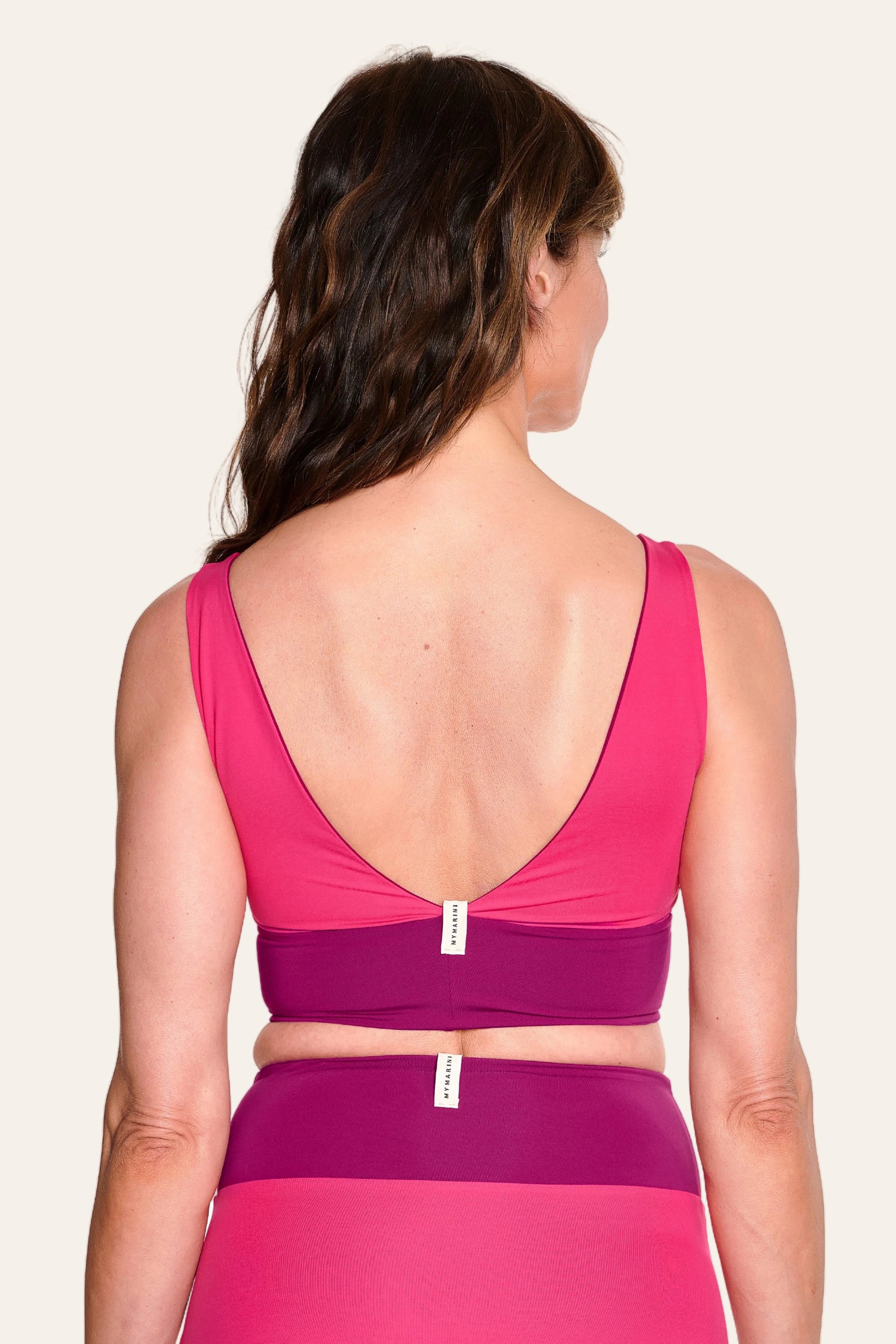 Frau trägt MYMARINI Bikinitop mit tiefem Rückenausschnitt und breiten Trägern in Pink.#color_pink-hortensia